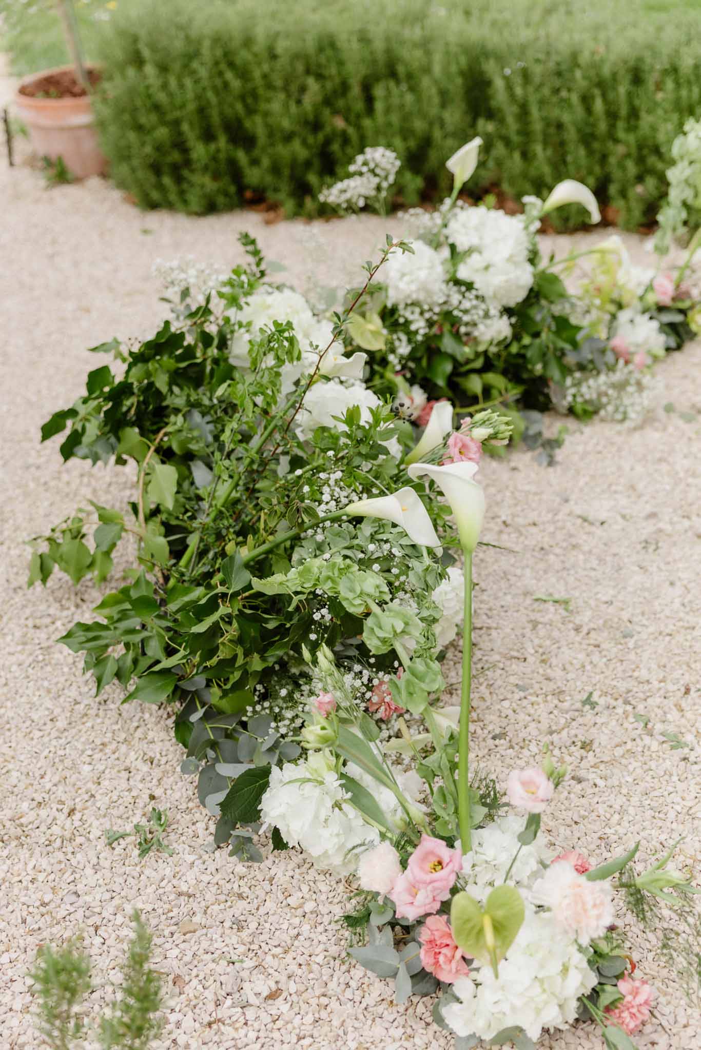 Close-up of white and blush floral arrangement along ceremony pathway at outdoor wedding venue