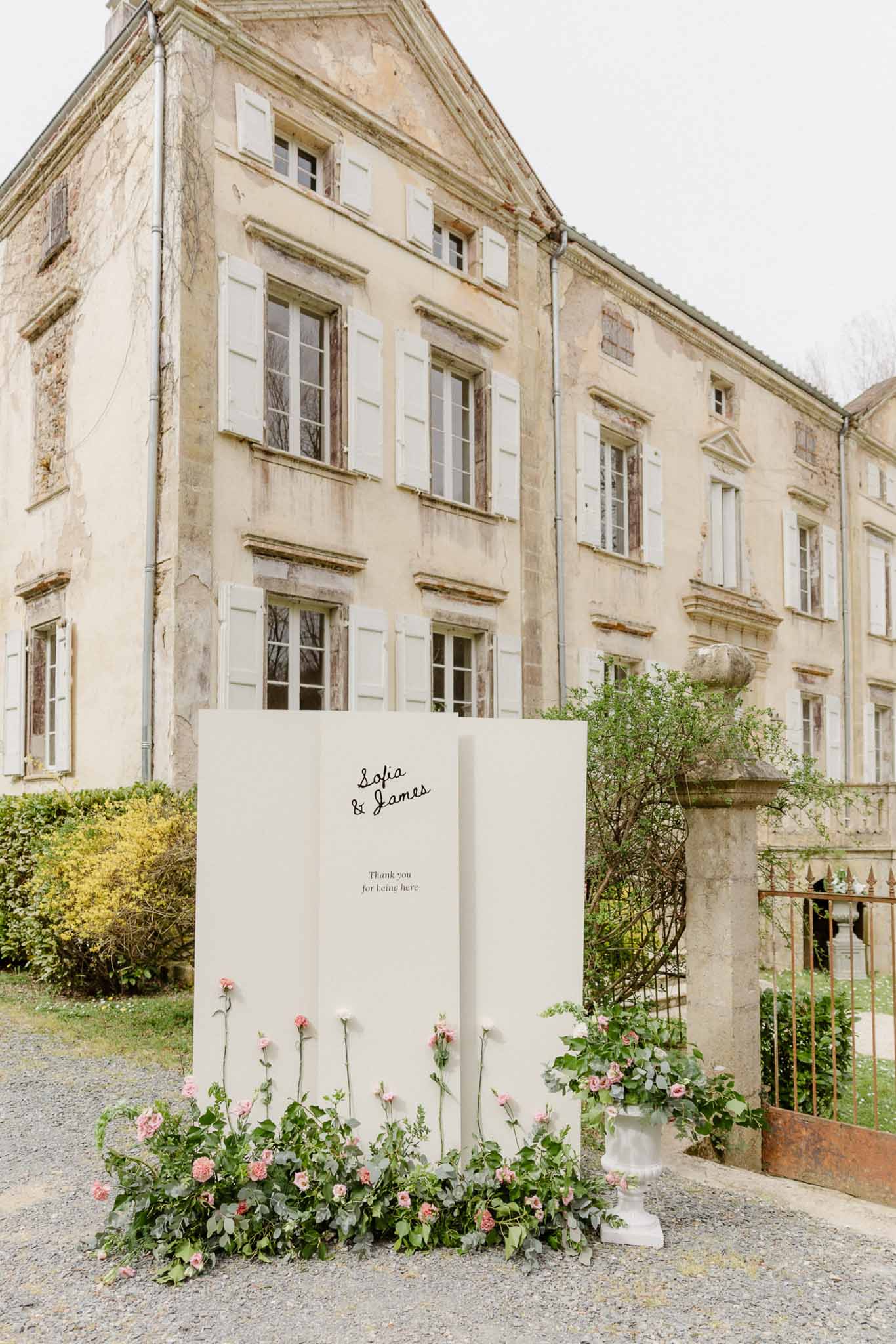 Wedding welcome sign with pink florals in historic château courtyard