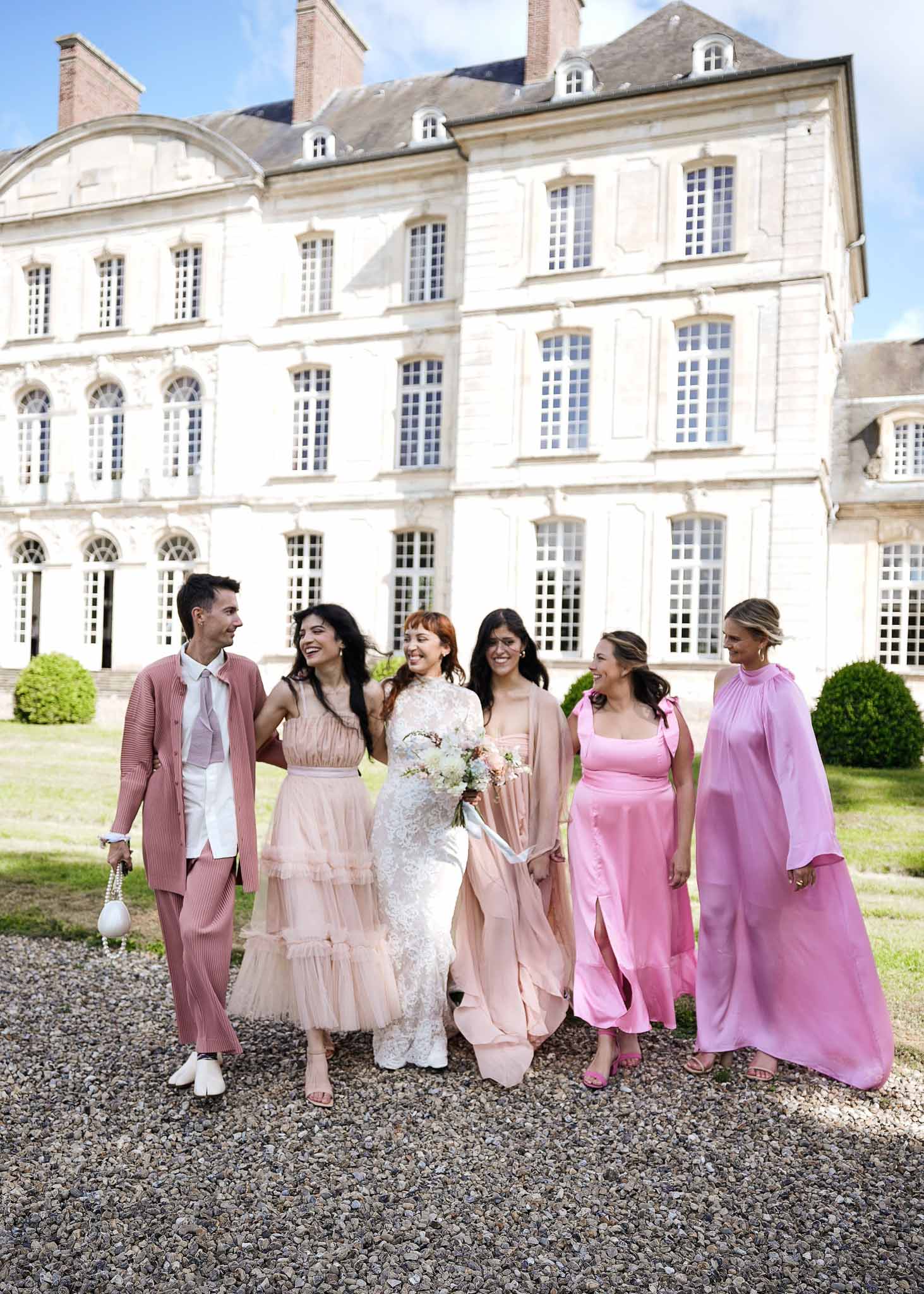 Bridal party portrait walking in front of French château with cream stone facade