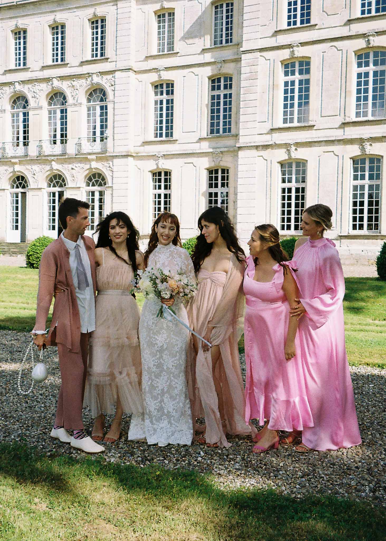Bride and bridal party group portrait at classical stone chateau with pastel coordinated attire