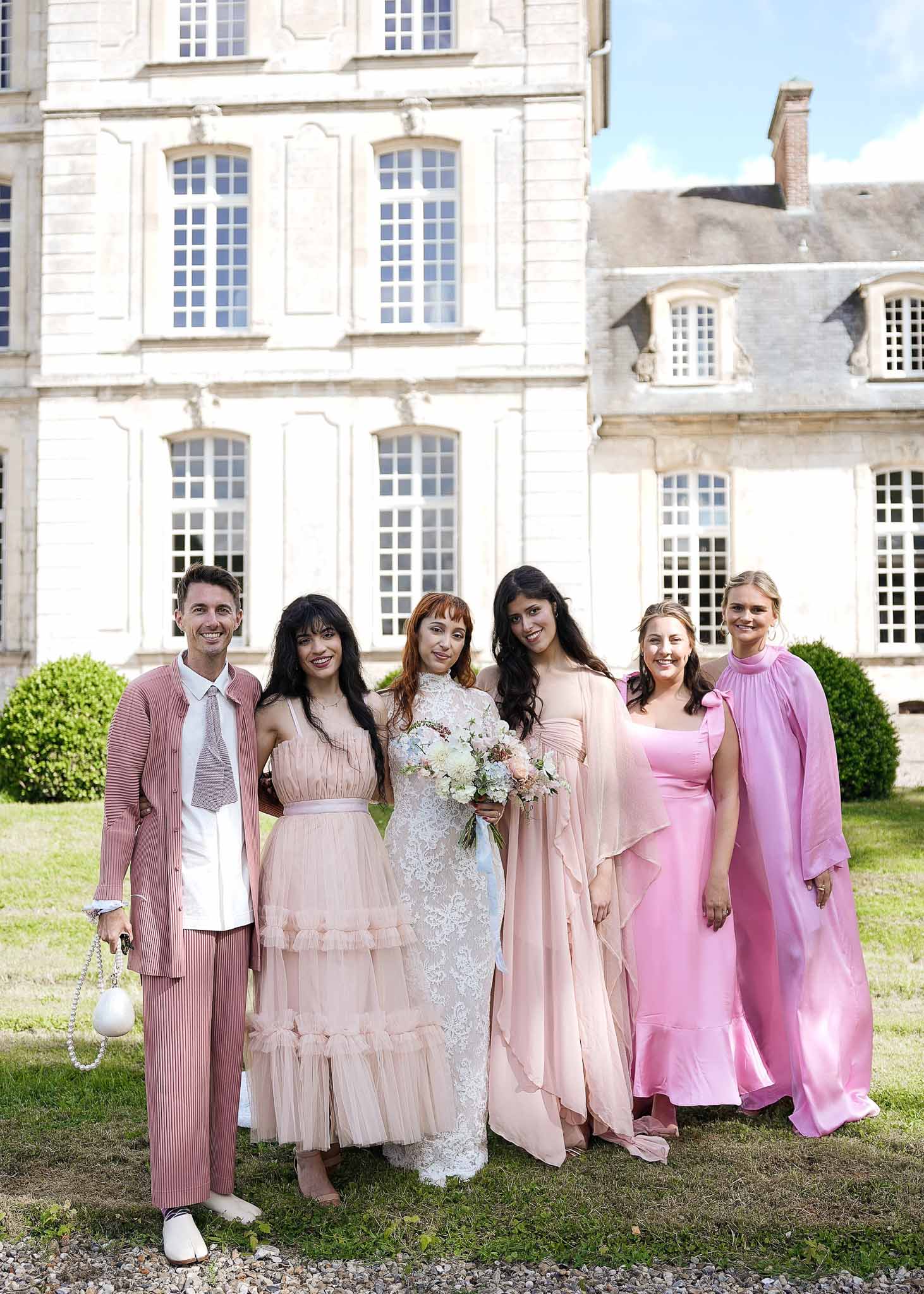 Bridal party portrait with bride and groom on château lawn with neoclassical architecture backdrop