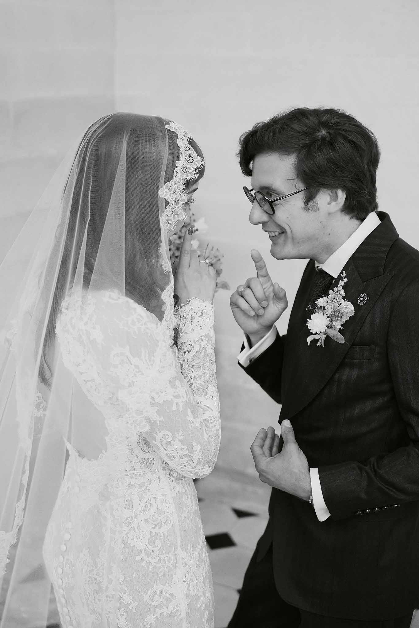 Black and white portrait of bride and groom in intimate candid moment, bride in lace dress with veil