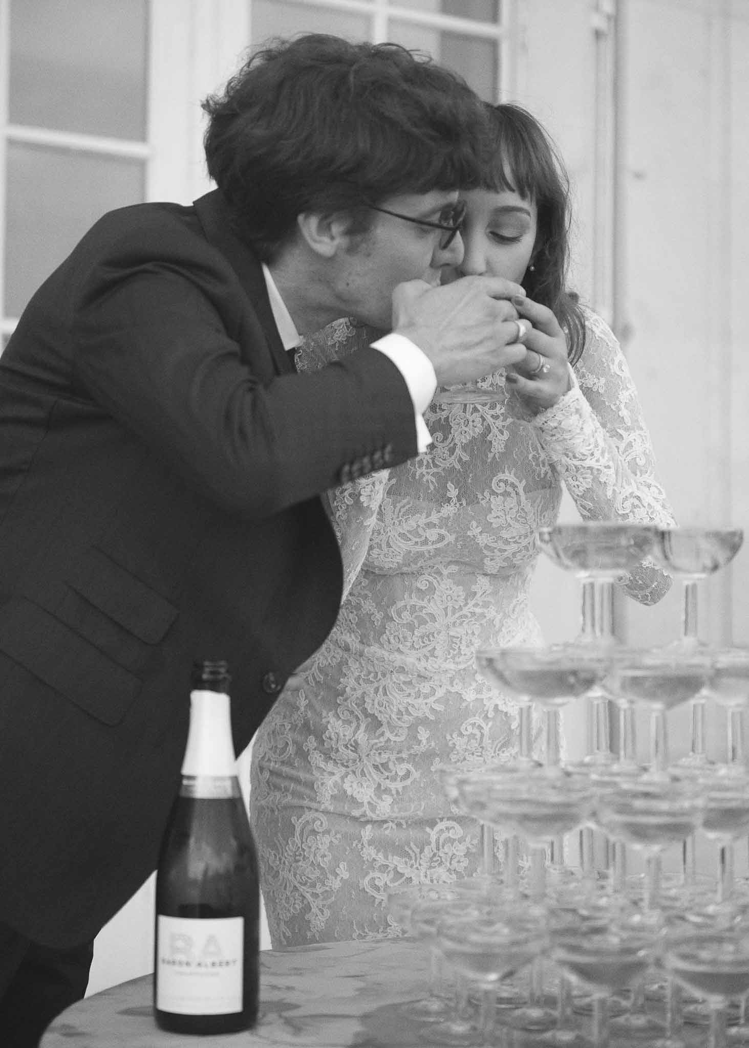 Groom kissing bride's hand during champagne toast at indoor wedding reception