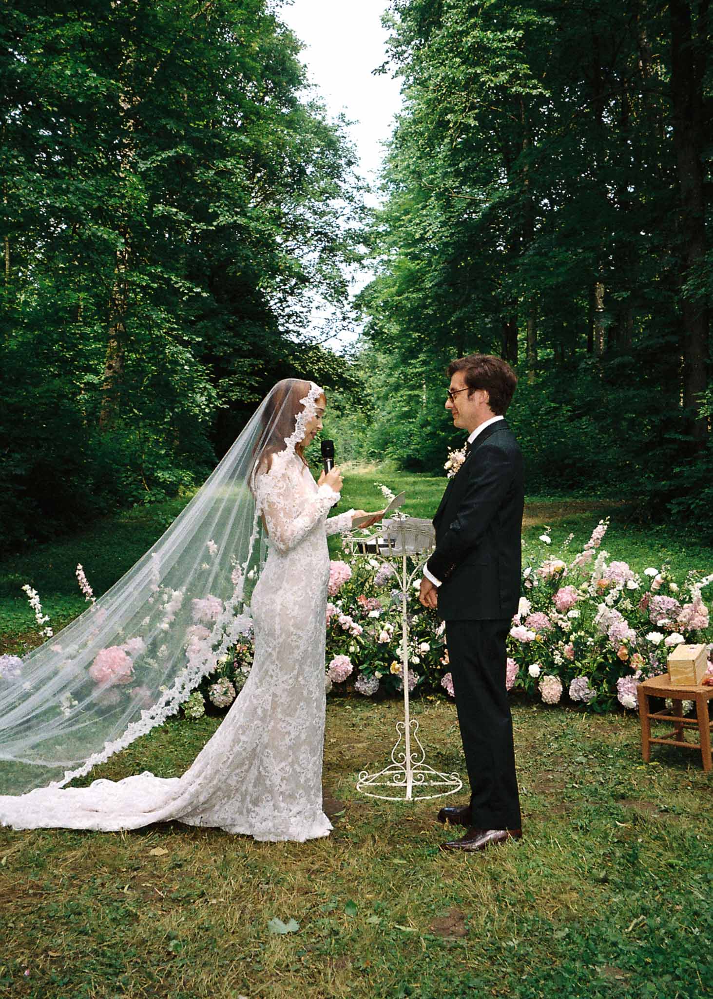 Bride and groom exchanging vows during outdoor ceremony in tree-lined garden setting