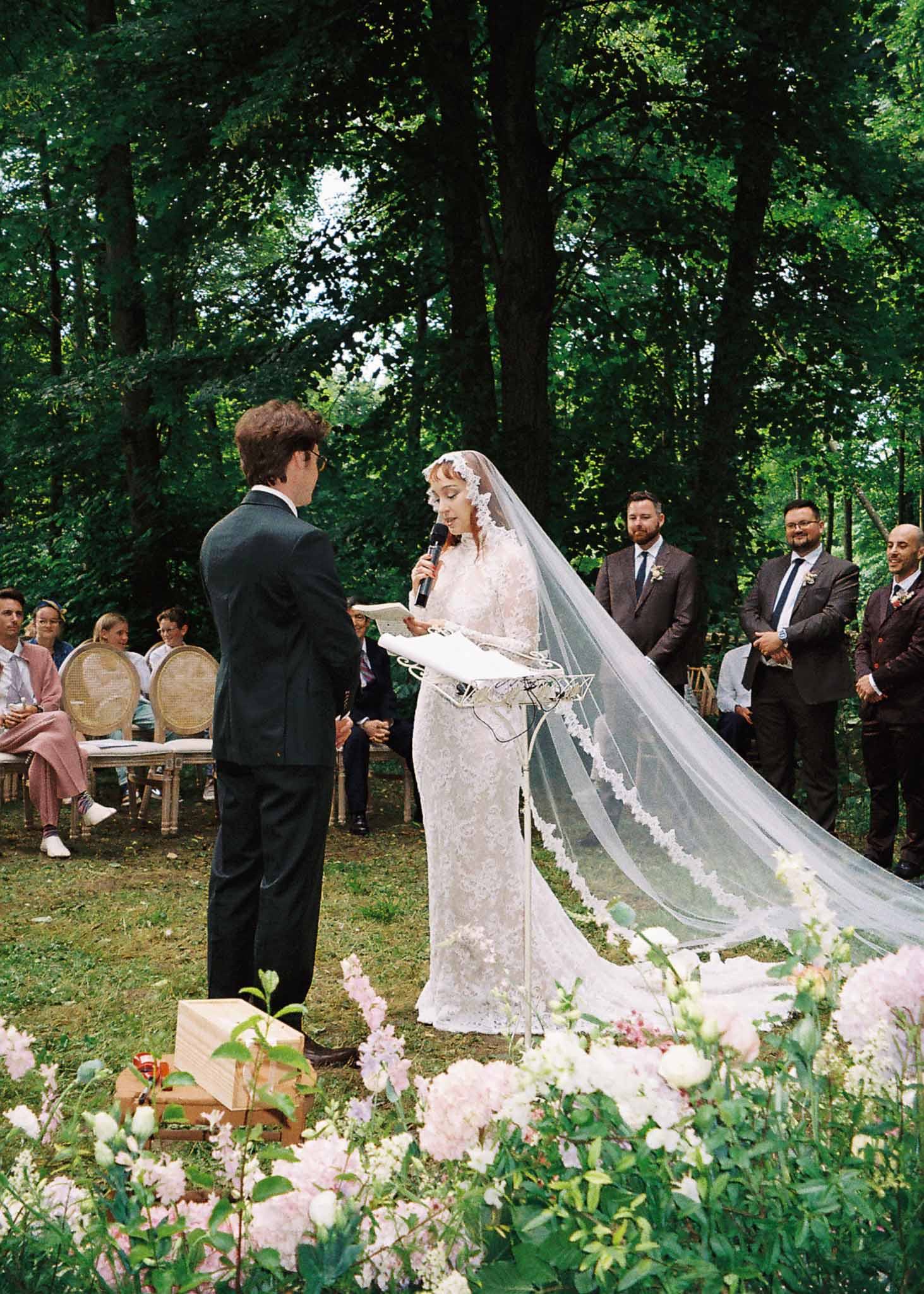Bride and groom exchanging vows during outdoor garden wedding ceremony with guests seated in chairs