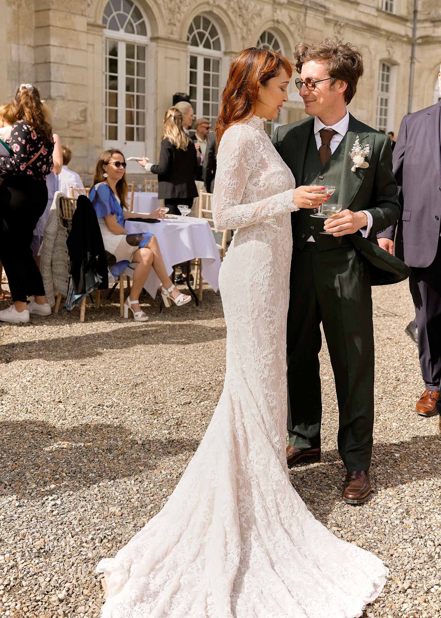 Bride and groom with champagne glasses during cocktail hour at classical stone courtyard venue
