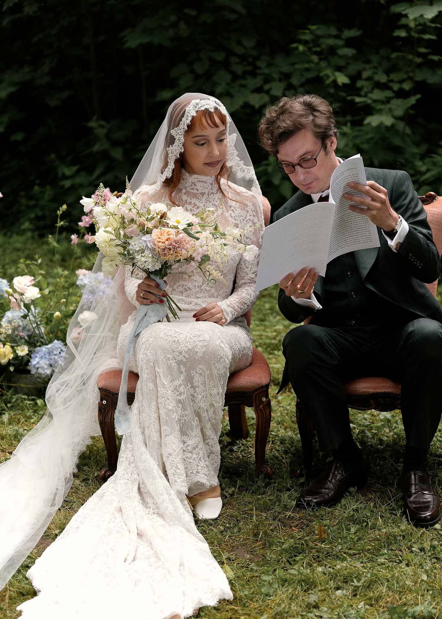 Bride and groom reading ceremony program together during outdoor garden wedding