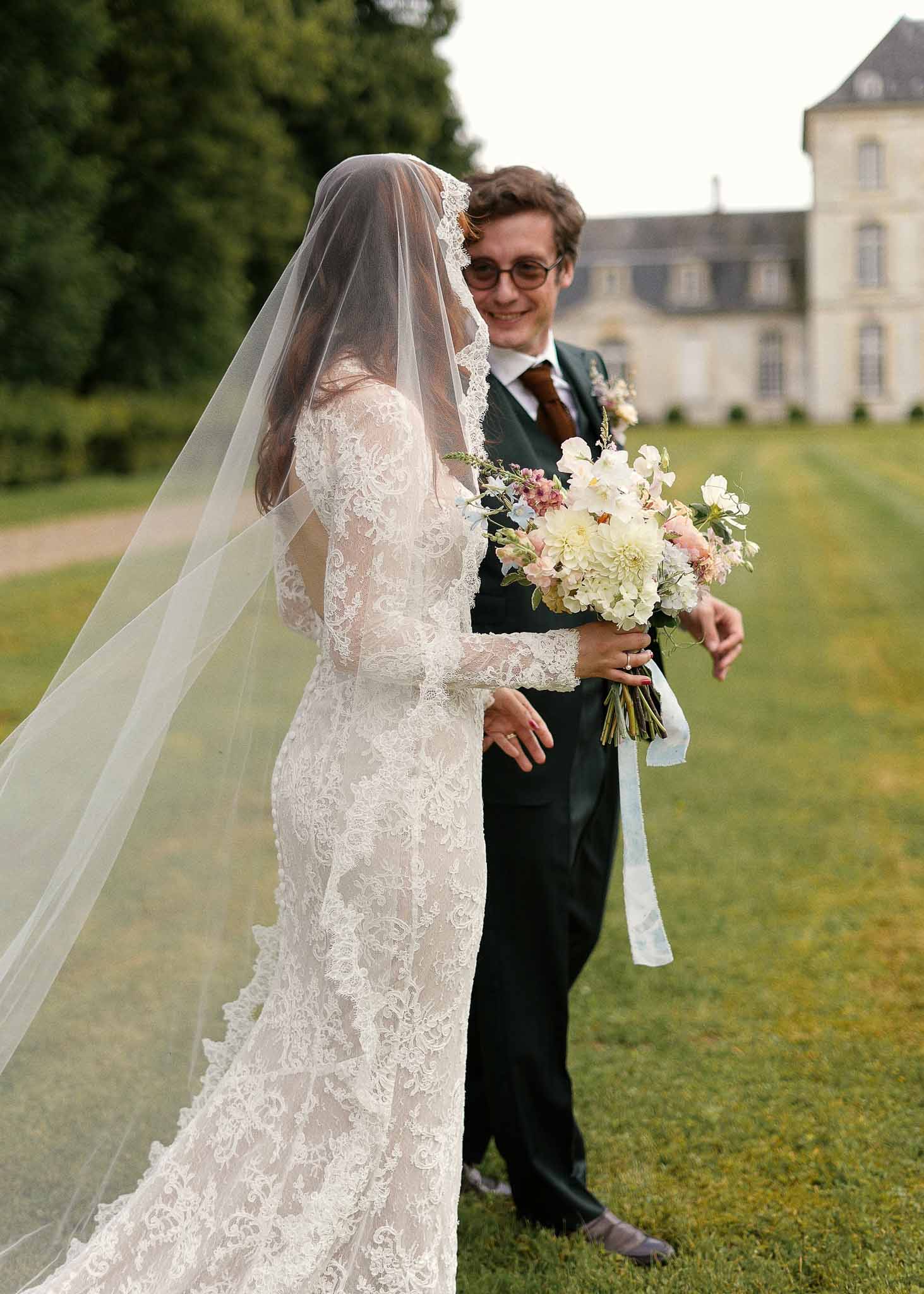 Bride and groom portrait on château estate lawn with classical architecture background