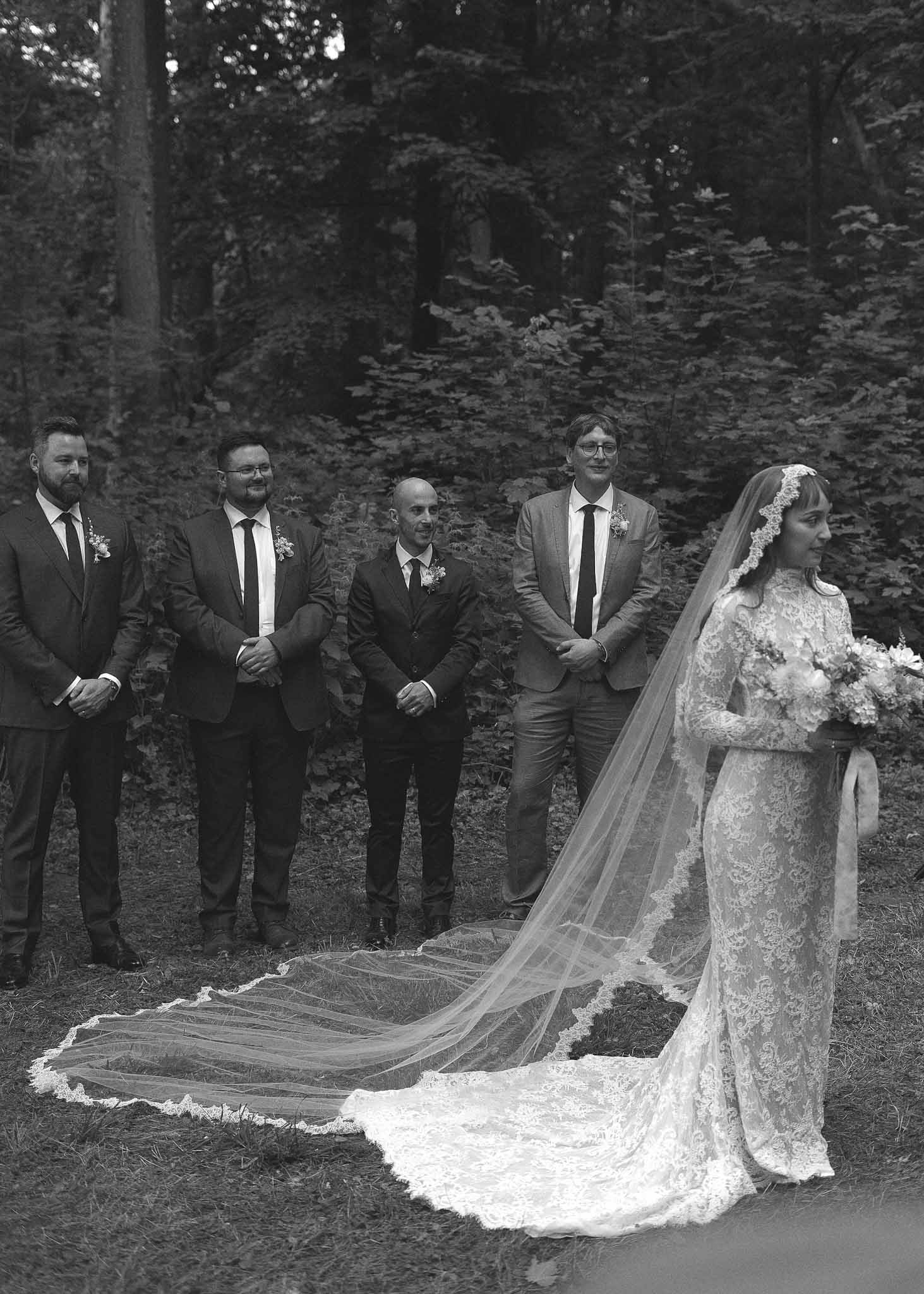 Black and white bridal party portrait with bride and groomsmen in forest setting