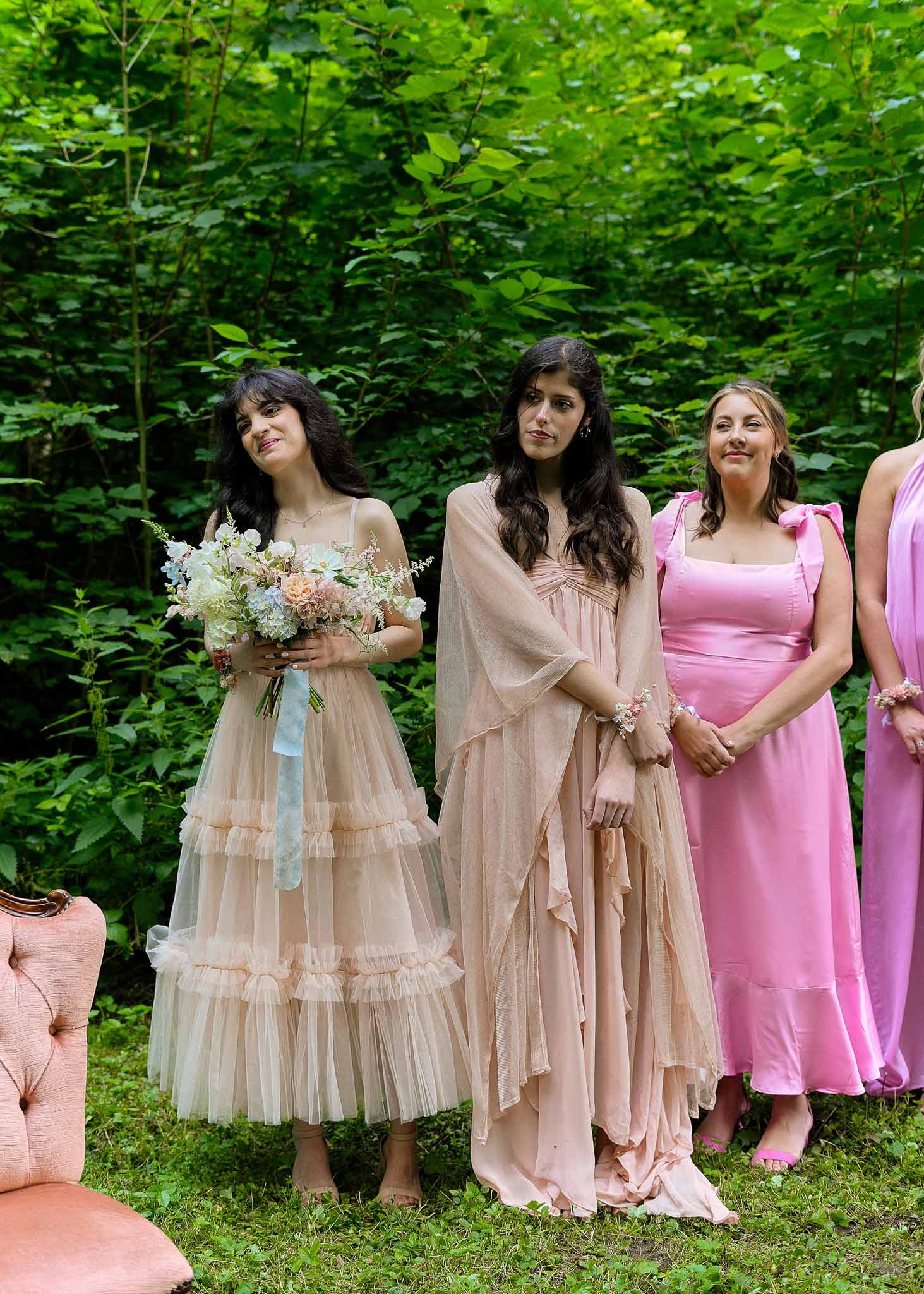 Bridal party group portrait in garden setting with mixed bouquets and coordinated dresses