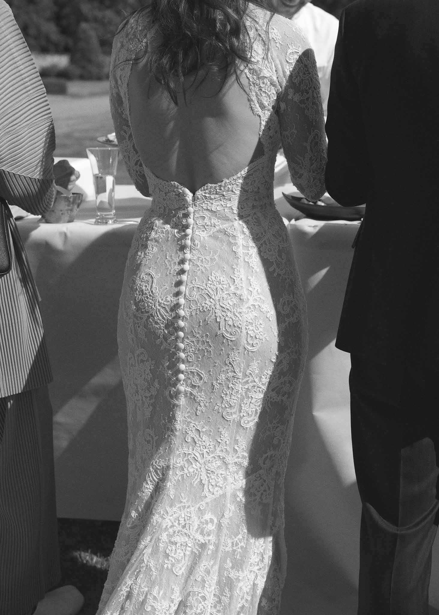 Bride's lace wedding dress with button details during reception dinner at wedding venue