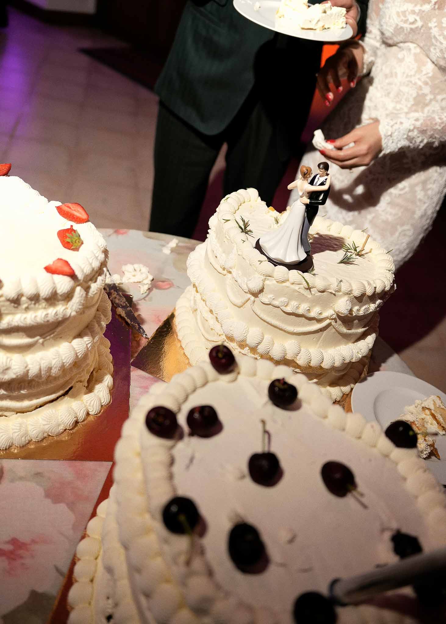 Bride and groom cutting wedding cake during reception with strawberry decorations and ambient lighting