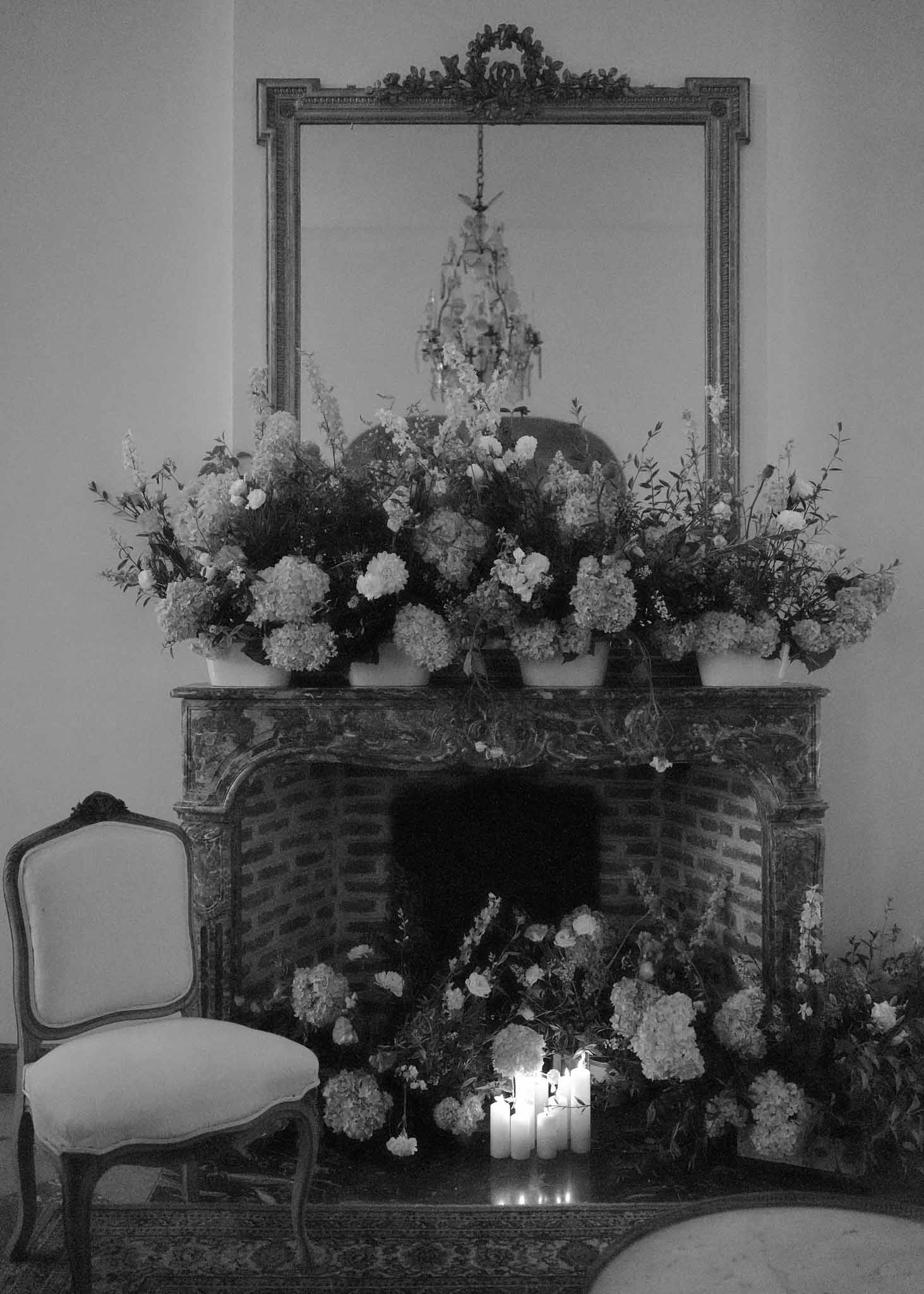 Ornate fireplace mantel with white floral arrangements and candles at elegant château reception