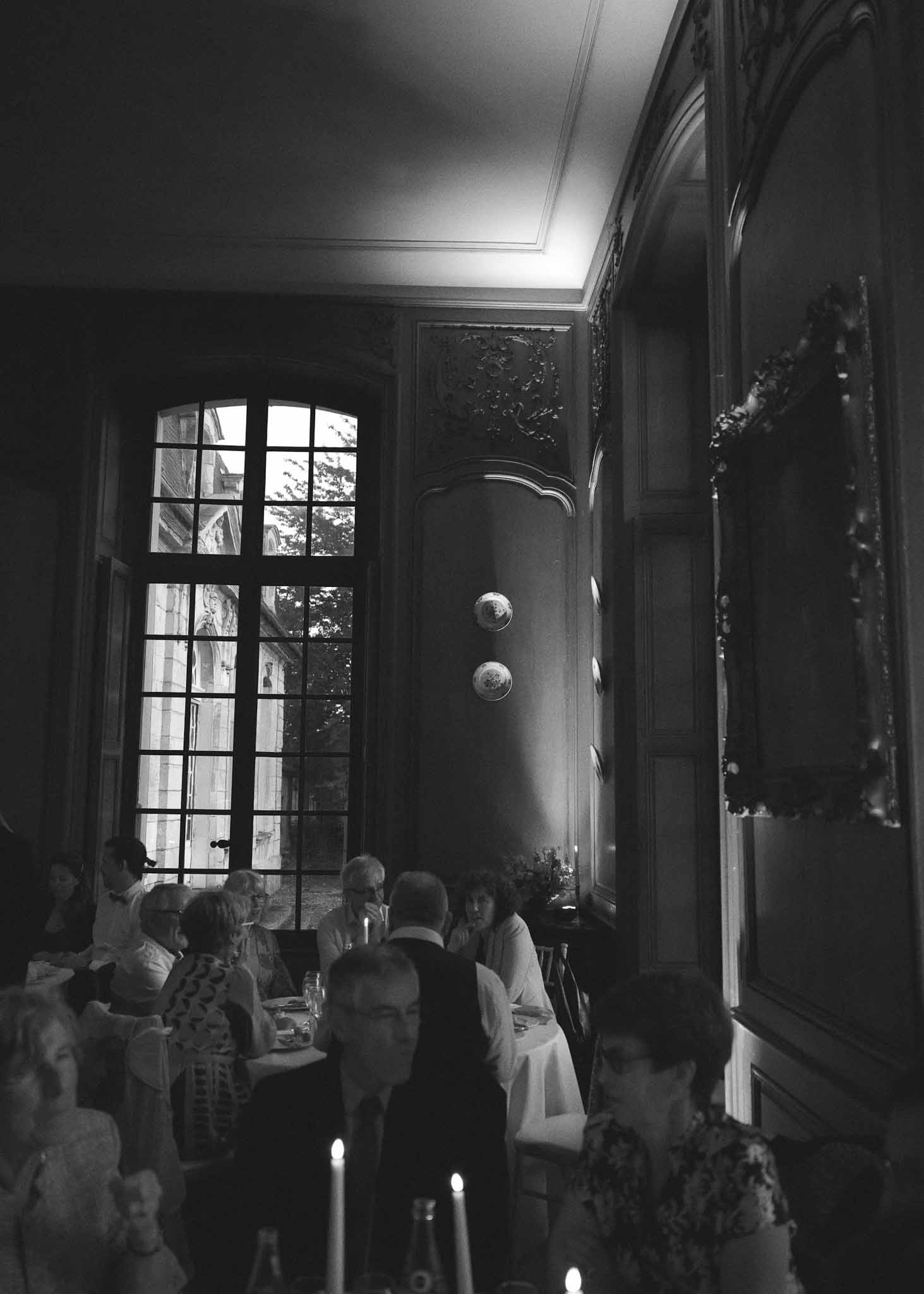 Black and white reception dinner scene in classical interior dining room with French doors and ornate paneling
