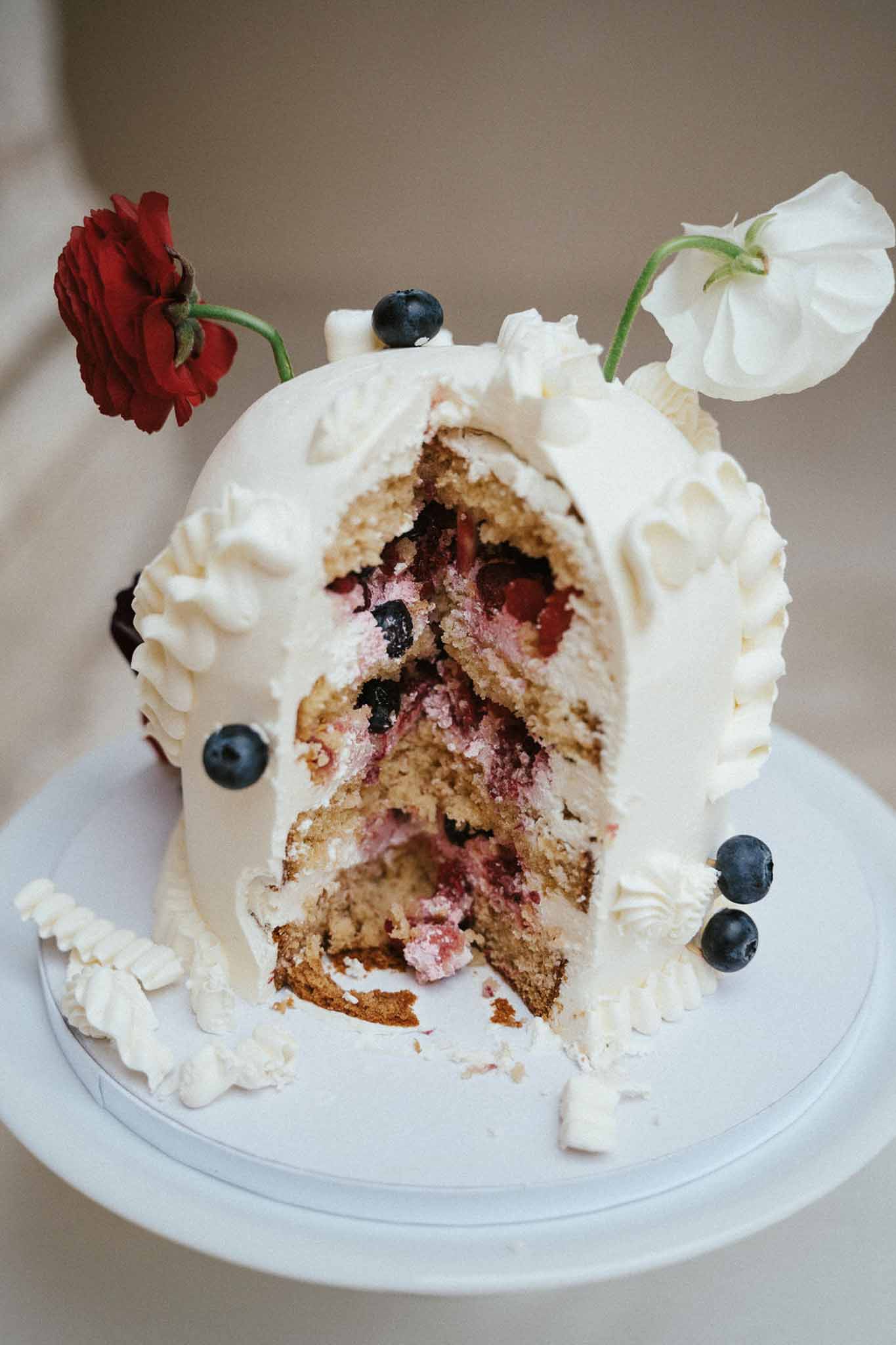 Wedding cake detail showing interior layers with berry filling and fresh floral decorations