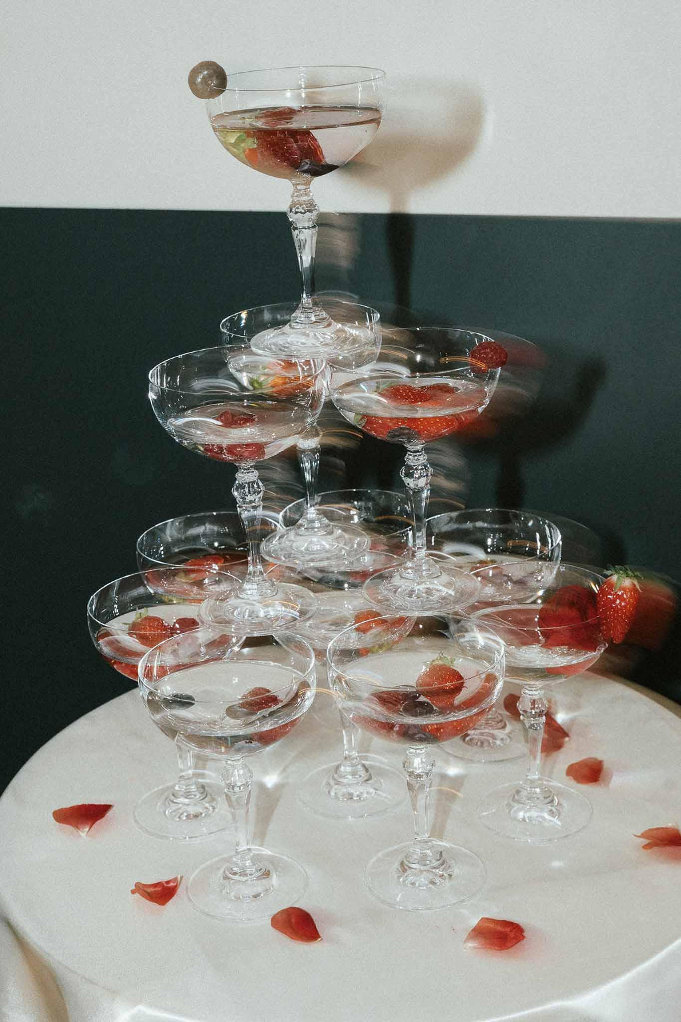 Champagne coupe tower with strawberries and rose petals at wedding reception
