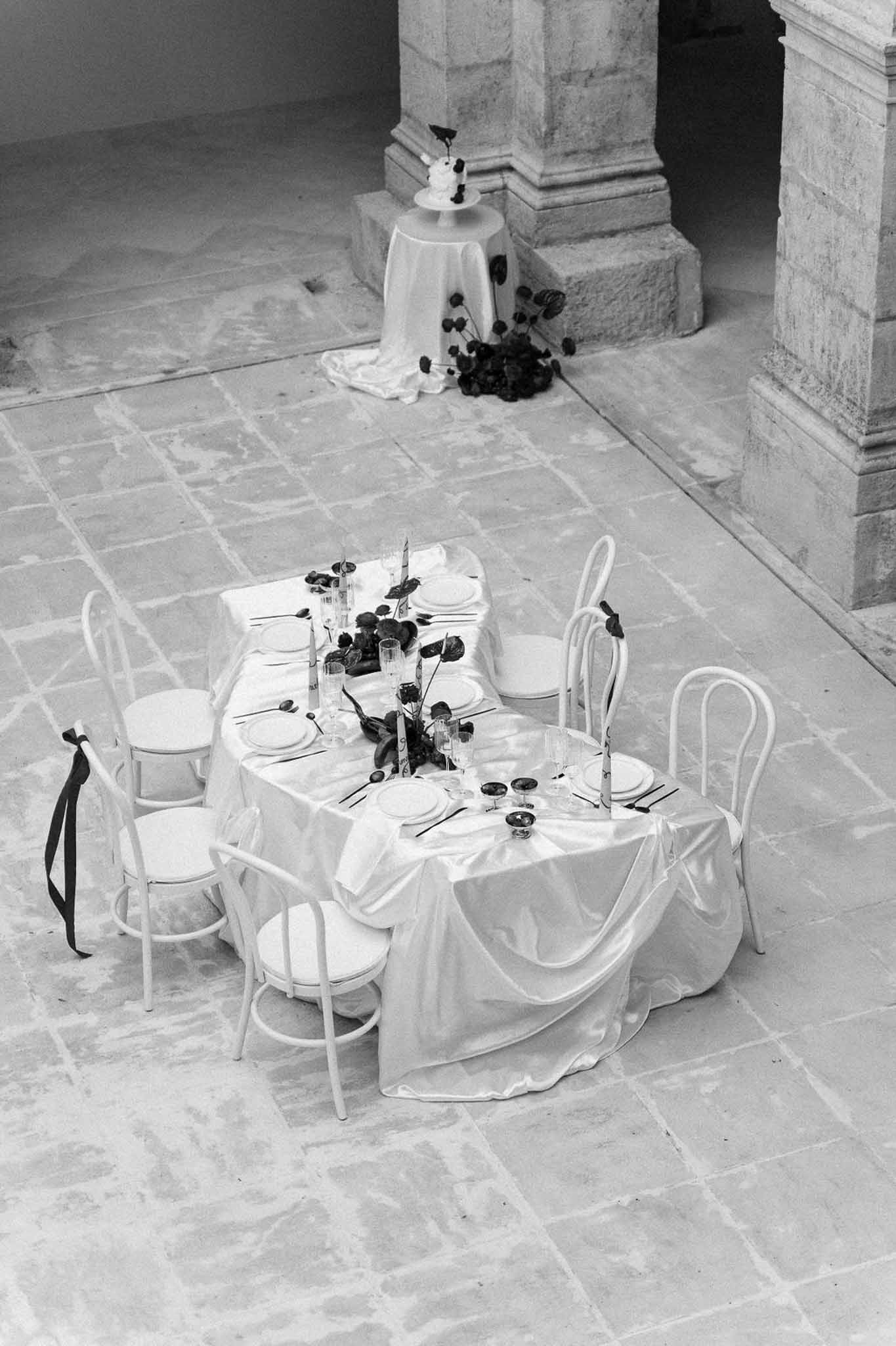 Aerial view of intimate reception setup in stone courtyard with round table and wedding cake display