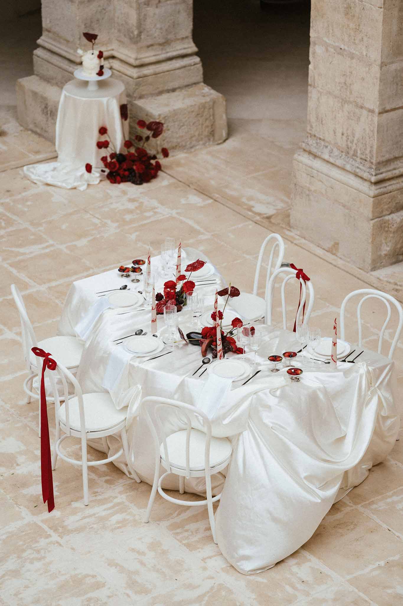 Minimalist reception table setup with red roses in stone courtyard with classical columns