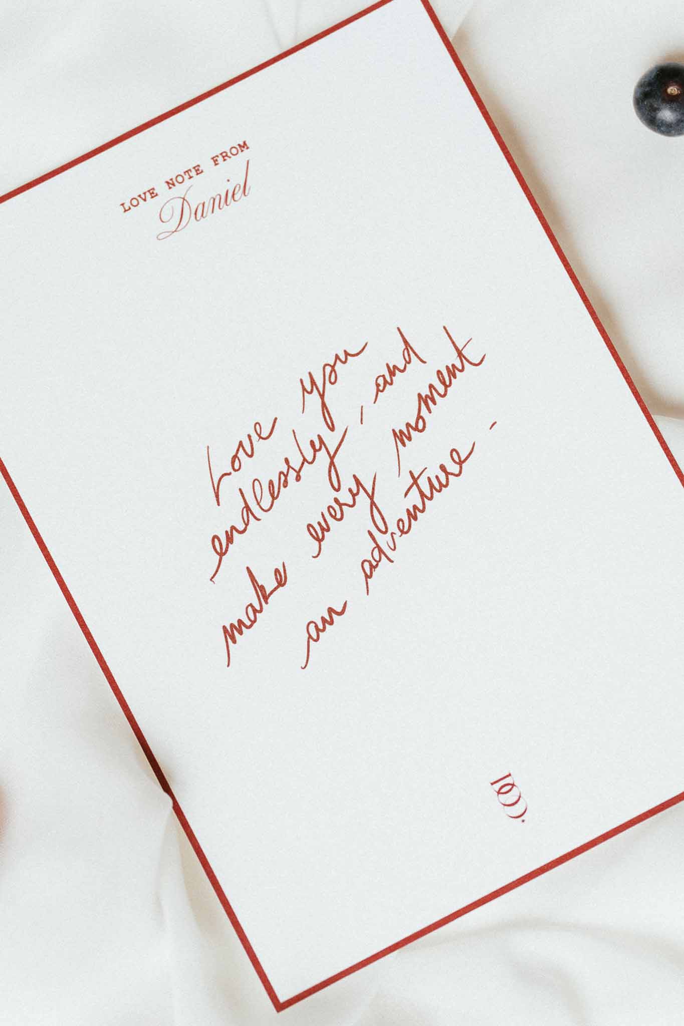 Personalised wedding love note card with deep red border and handwritten message on white fabric