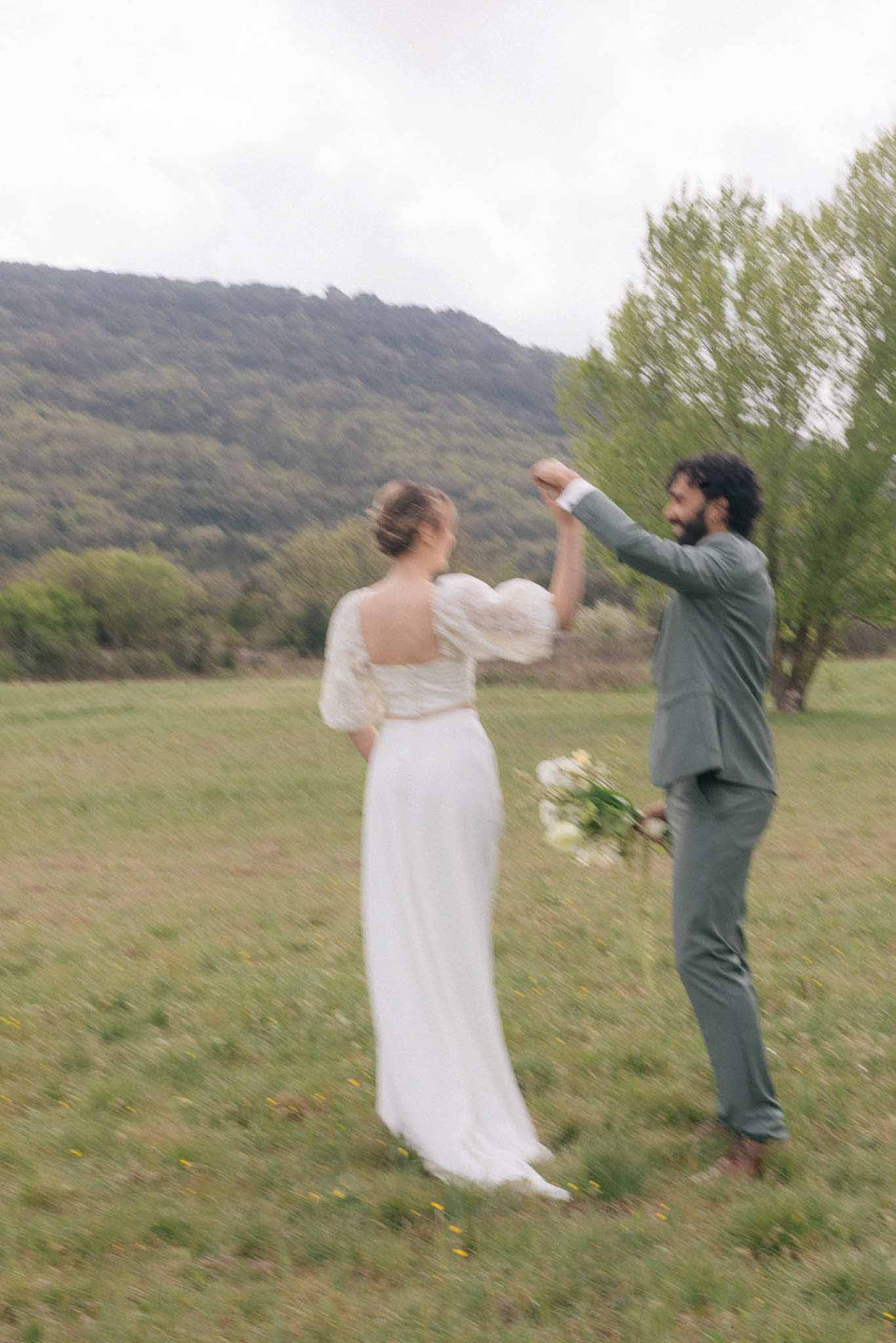 Couple's first dance in open meadow with forested hills at outdoor wedding reception