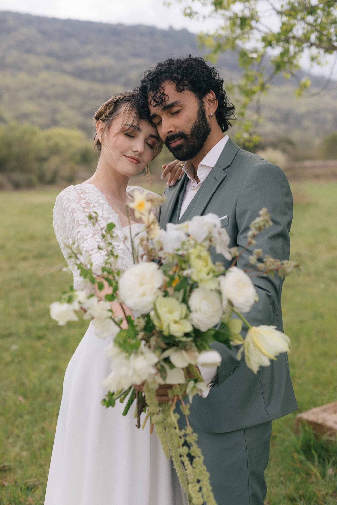 Bride and groom intimate portrait in open field with mountain backdrop