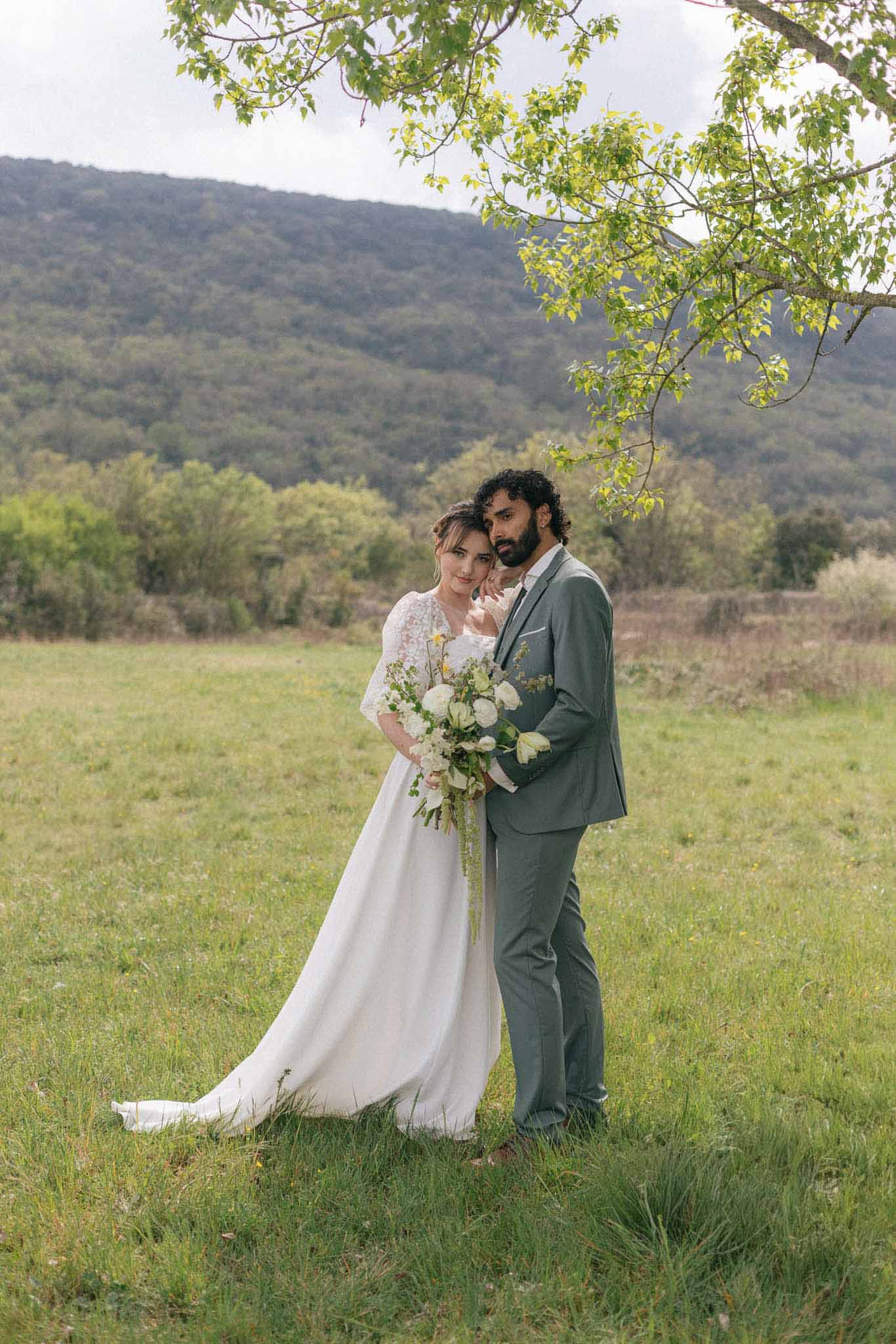 Bride and groom portrait in countryside meadow with forested hills background