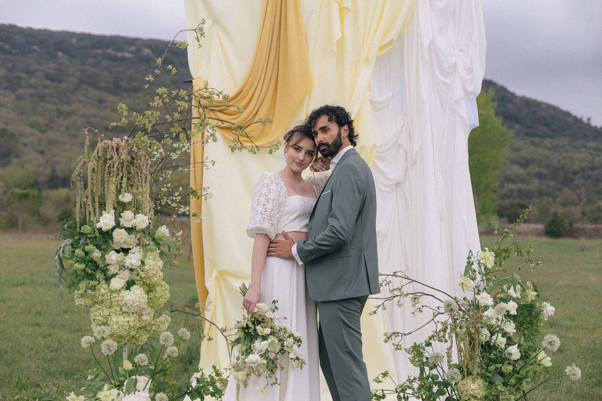 Bride and groom portrait under floral ceremony arch in outdoor garden setting