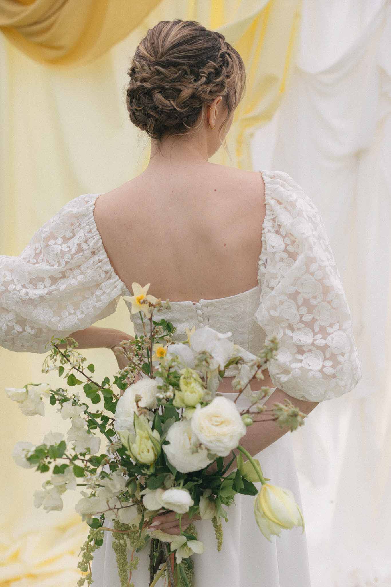 Bride in ivory embellished dress holding cascading bouquet in indoor portrait setting