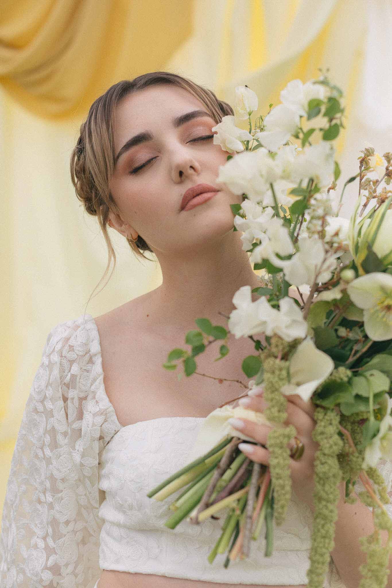 Bride holding white flower bouquet in close-up portrait with ivory lace dress
