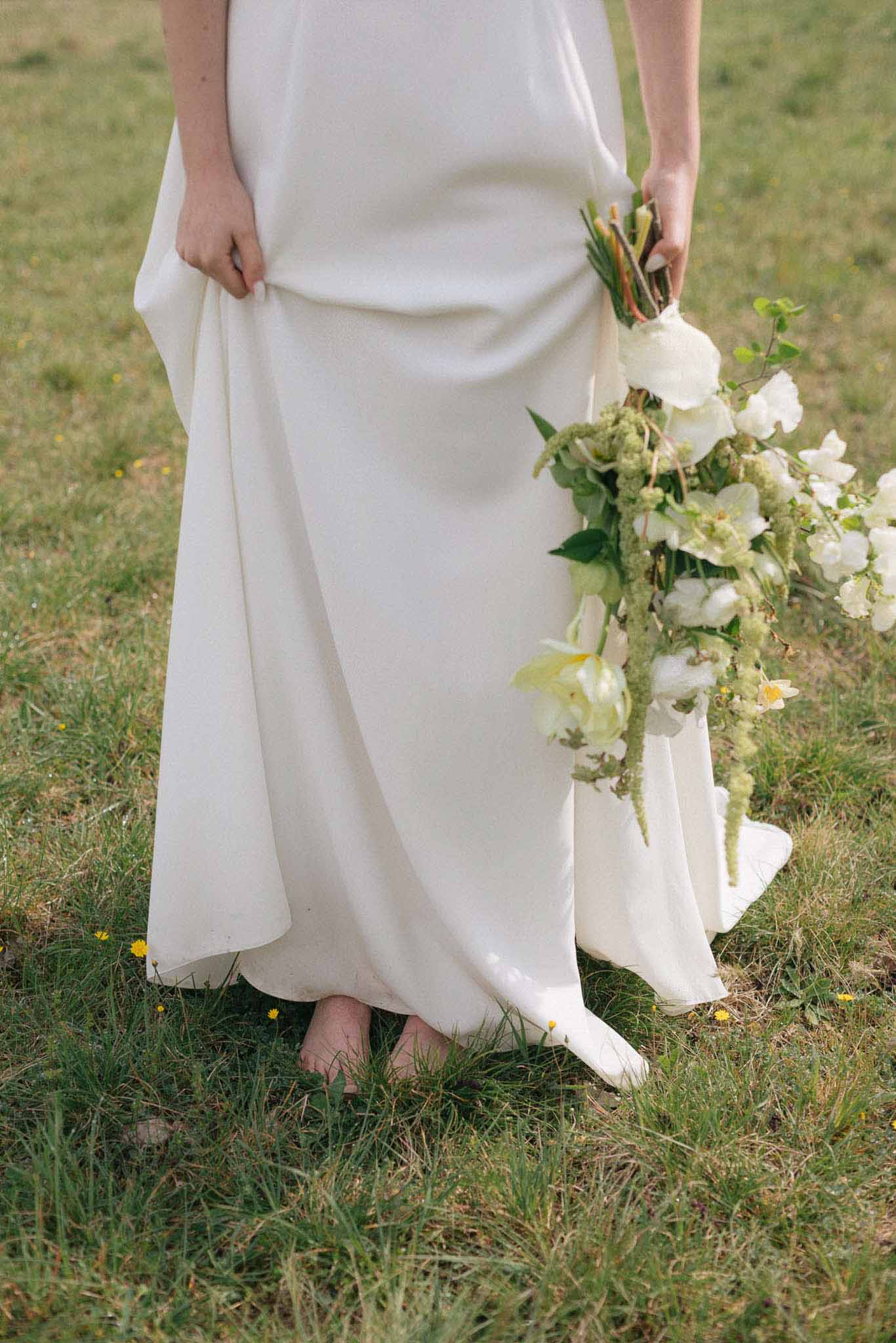 Bride in ivory dress holding white bouquet during outdoor portrait session