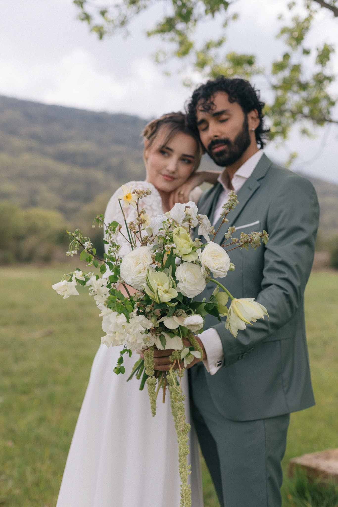 Bride and groom portrait in open field with mountain backdrop for outdoor wedding