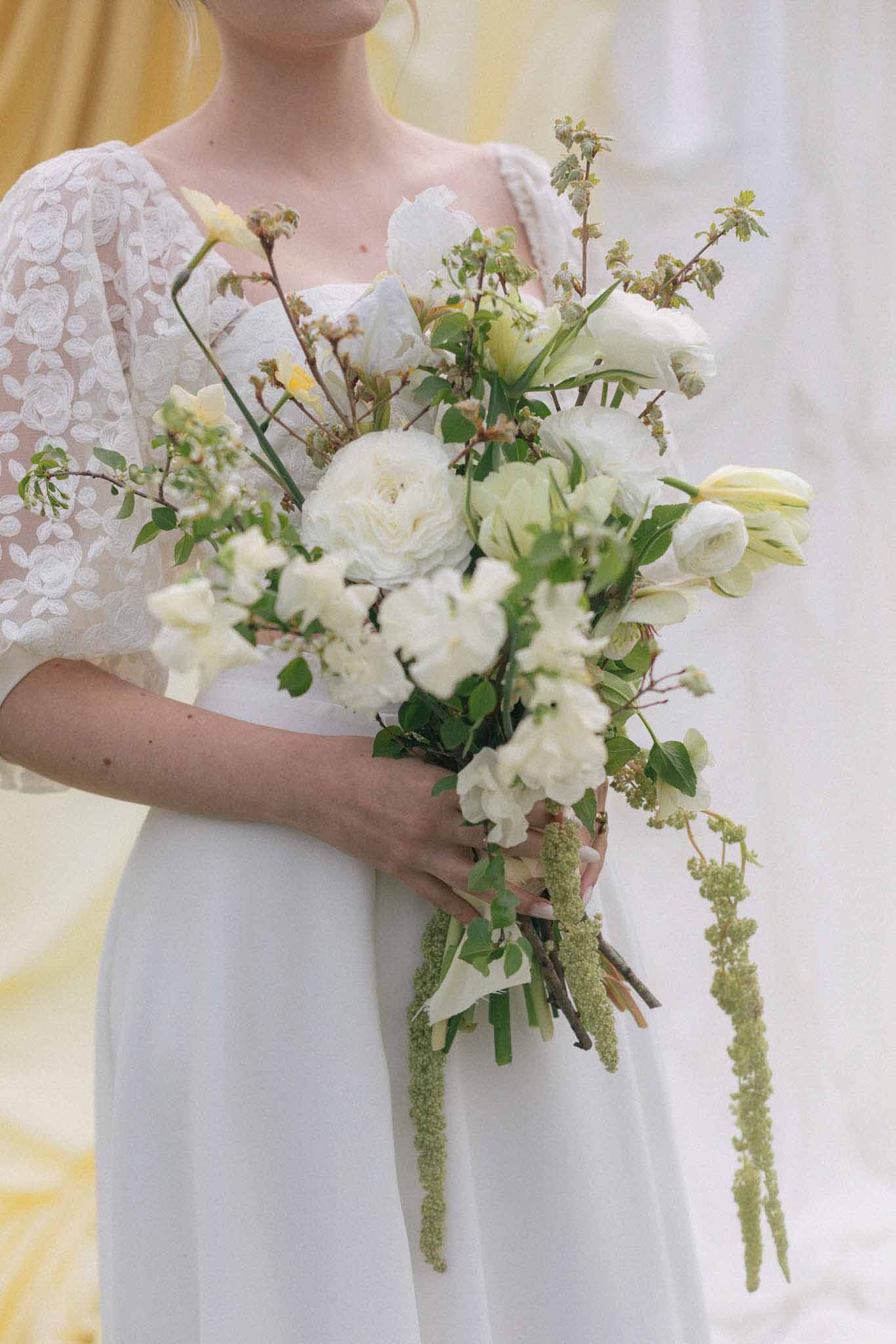 Bride holding ivory and green wedding bouquet during portrait session