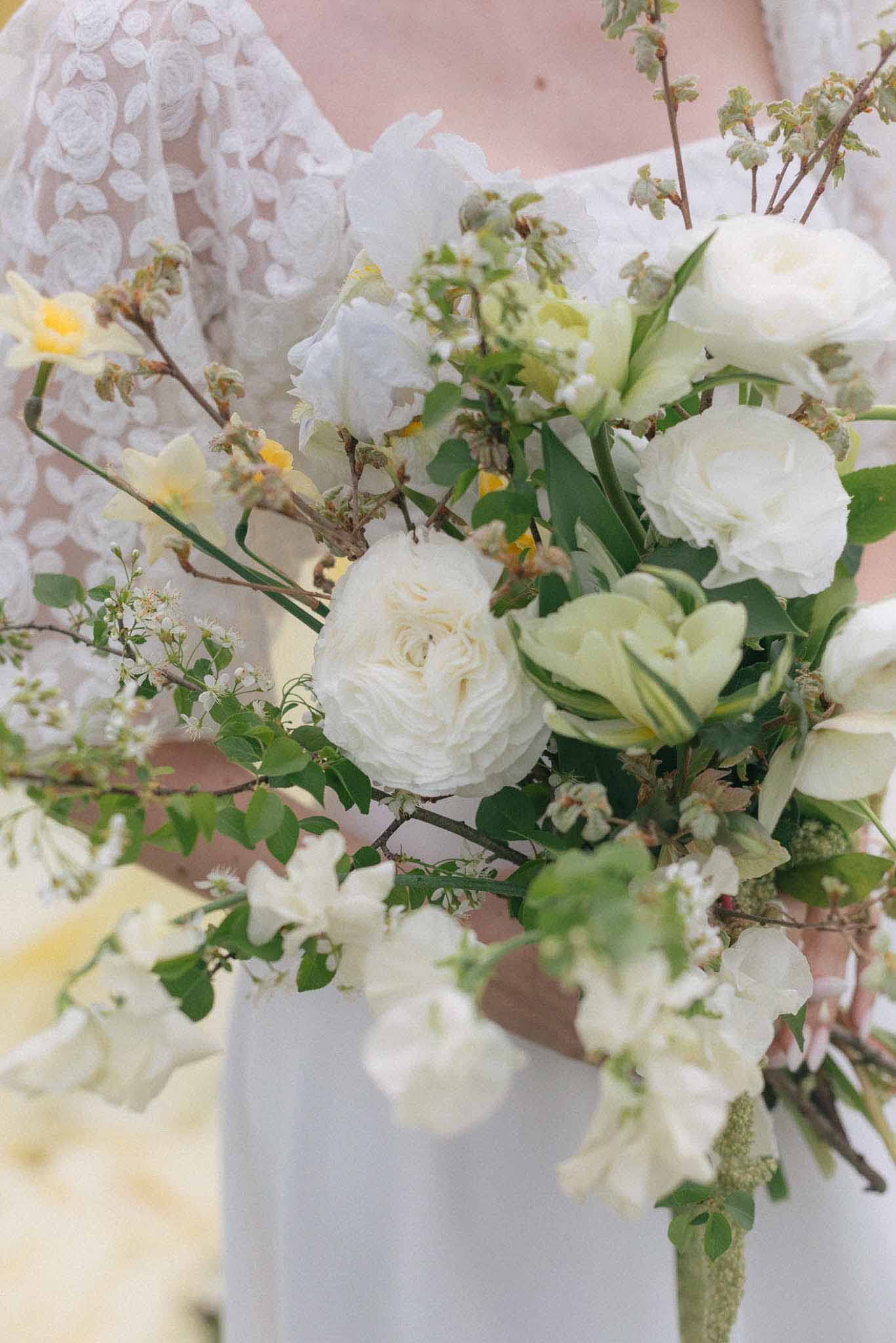 Bridal bouquet with white roses and ranunculus against lace wedding dress
