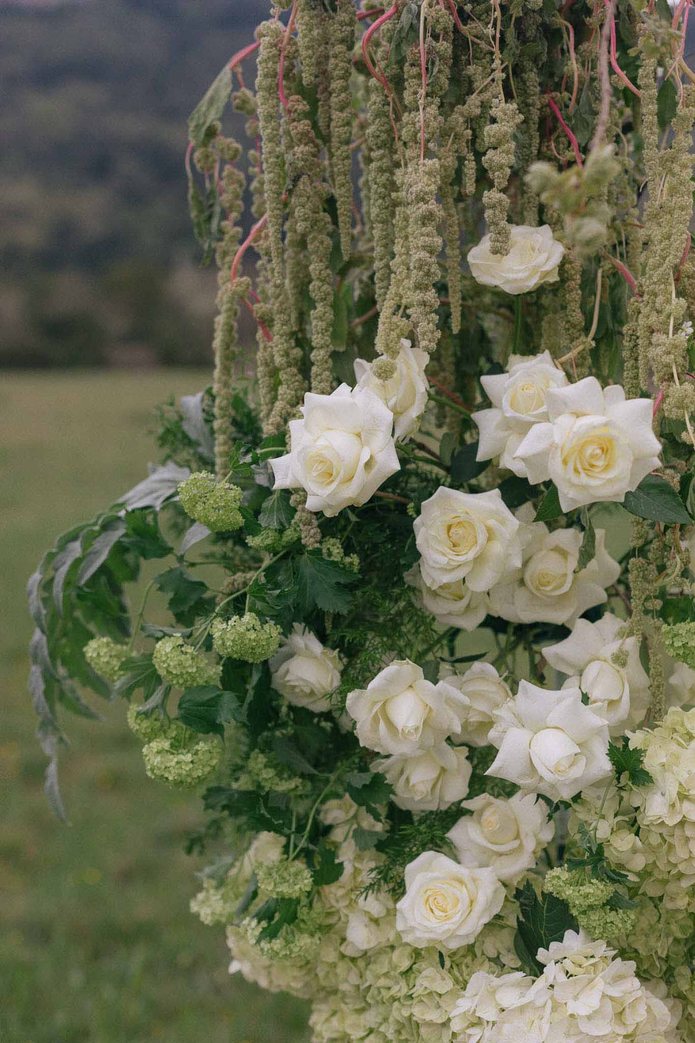 Close-up of hanging floral arrangement with cream roses and cascading amaranthus at outdoor garden wedding