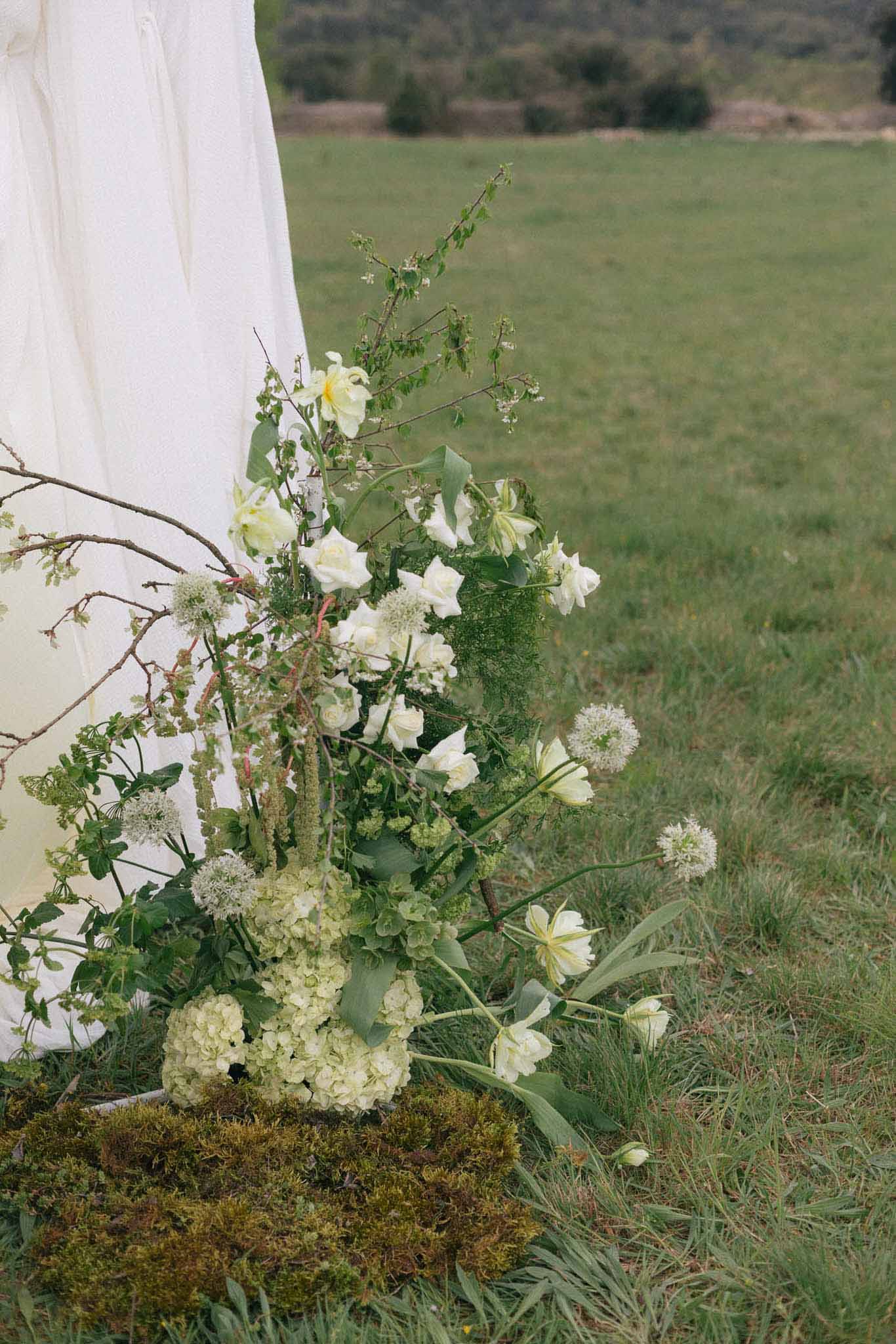 Cream and pale yellow floral installation with roses and hydrangea at outdoor countryside ceremony venue