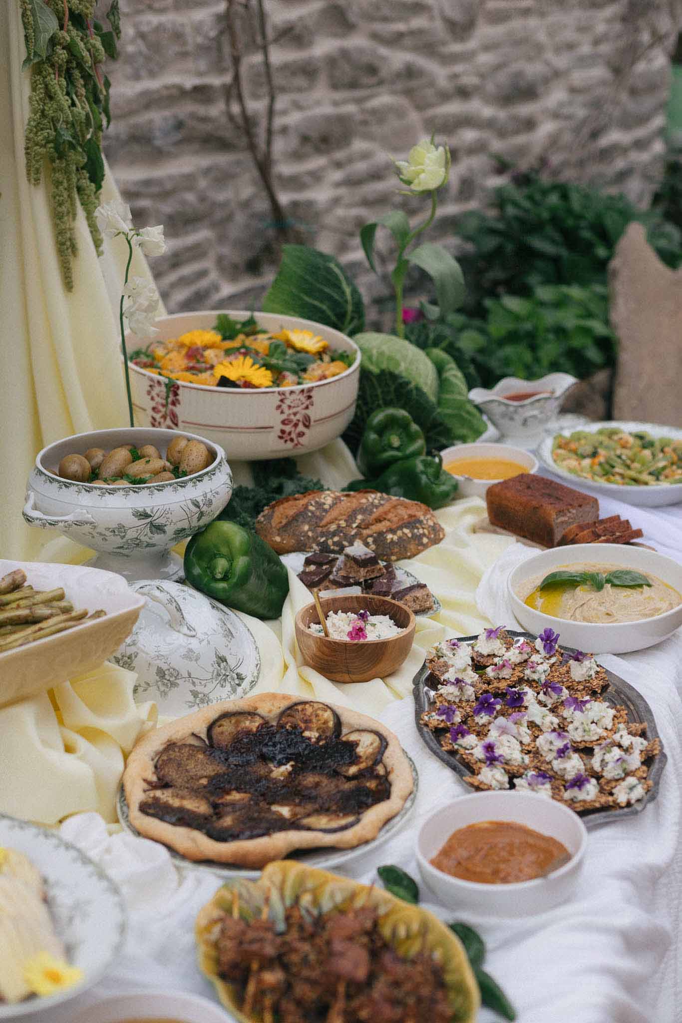Mediterranean food display with botanical tableware and yellow flowers at outdoor wedding reception