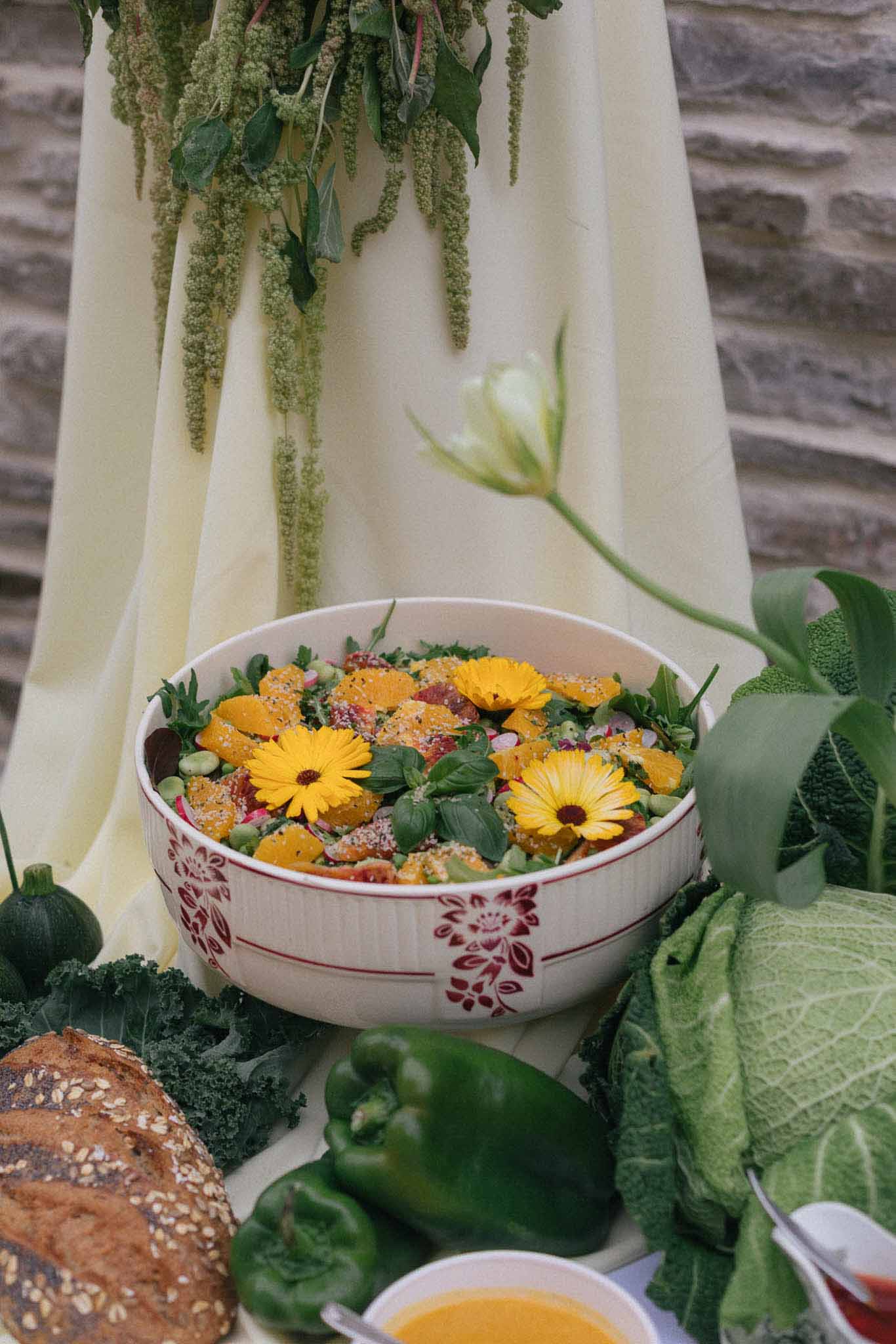 Wedding reception food display with floral ceramic bowl and botanical backdrop at garden-themed venue