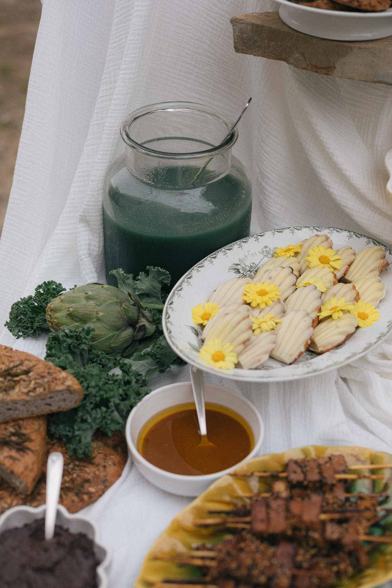 Wedding reception food and beverage flat lay display on white linen with garnished poultry and fresh produce