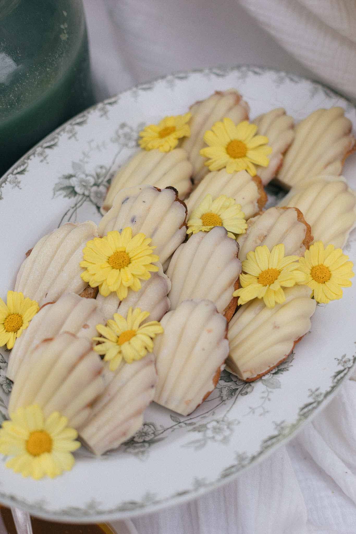 Wedding dessert pastries with pink icing and yellow daisy flowers on floral porcelain plate