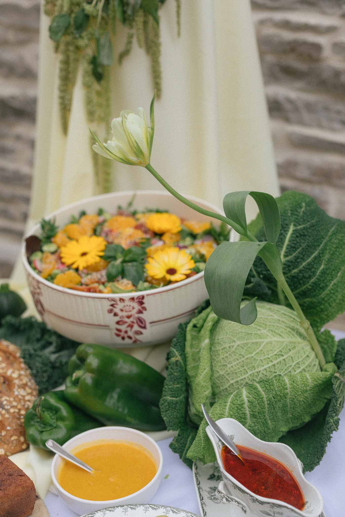 Garden-inspired table setting with yellow gerbera daisies and sage bundles at outdoor wedding reception