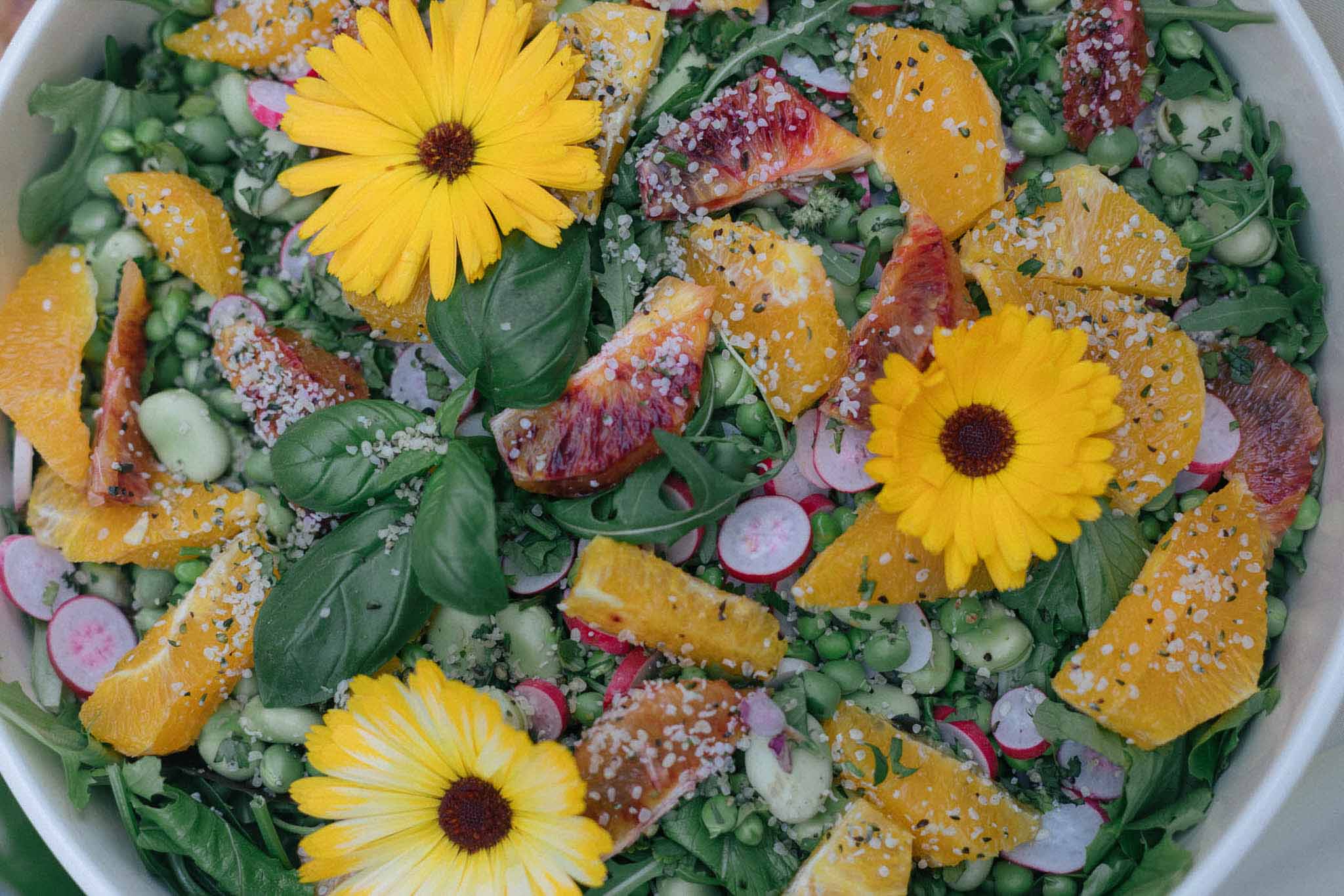 Colorful wedding salad with edible flowers and fresh vegetables in white bowl for reception dinner service