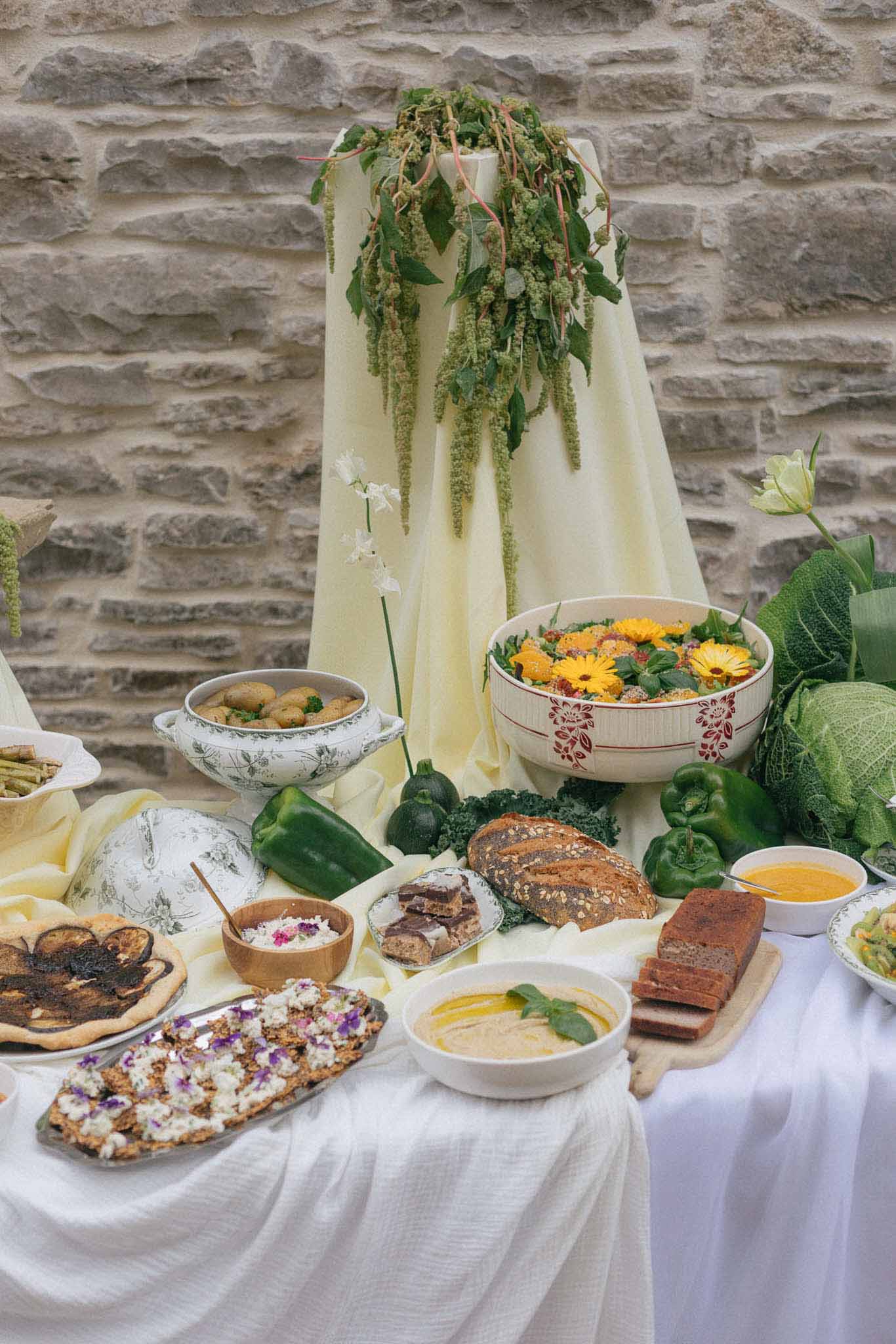 Styled food and floral display with artisanal dishes and cascading greenery at rustic wedding reception