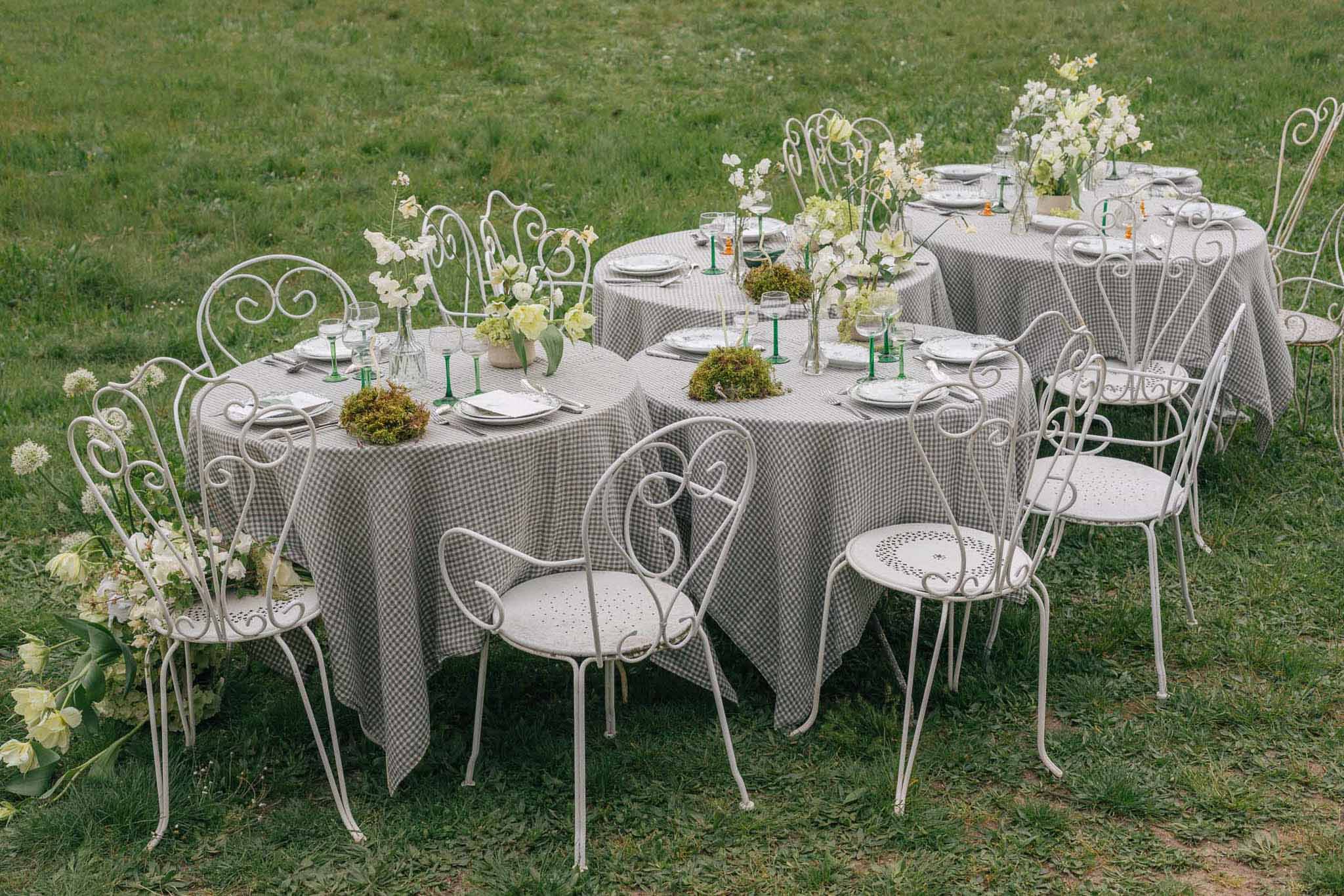 Outdoor wedding reception tables with gingham linens and white floral centerpieces on lawn