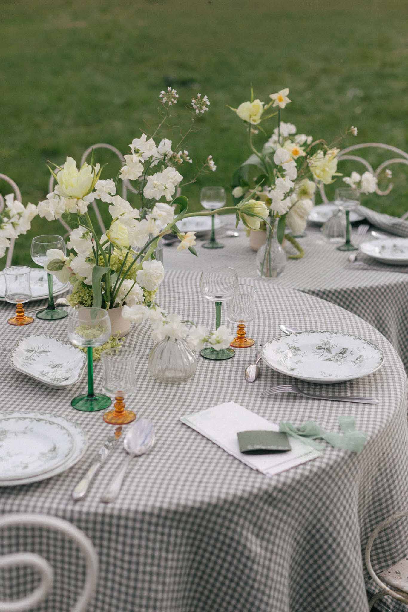 Outdoor reception tablescape with sage gingham linens and cream peony centerpieces at garden wedding