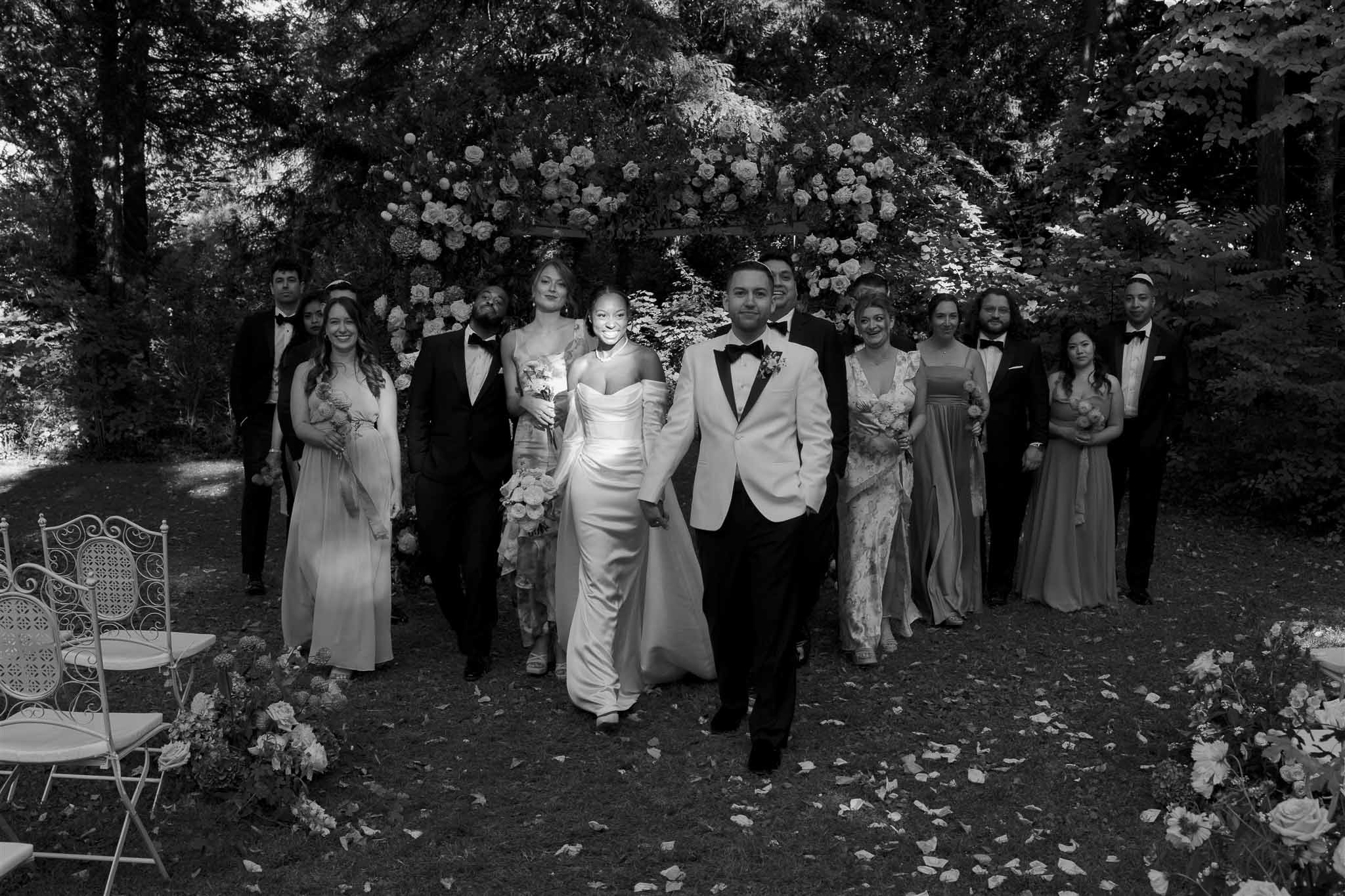 Wedding ceremony recessional with bride and groom walking down aisle in wooded garden setting