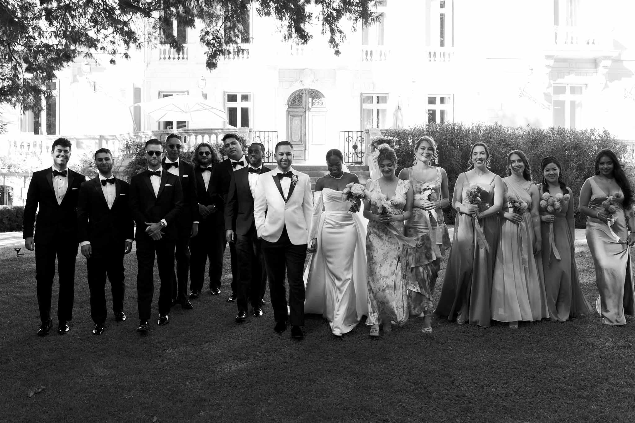 Formal bridal party portrait with bride, groomsmen, and bridesmaids at classical mansion courtyard
