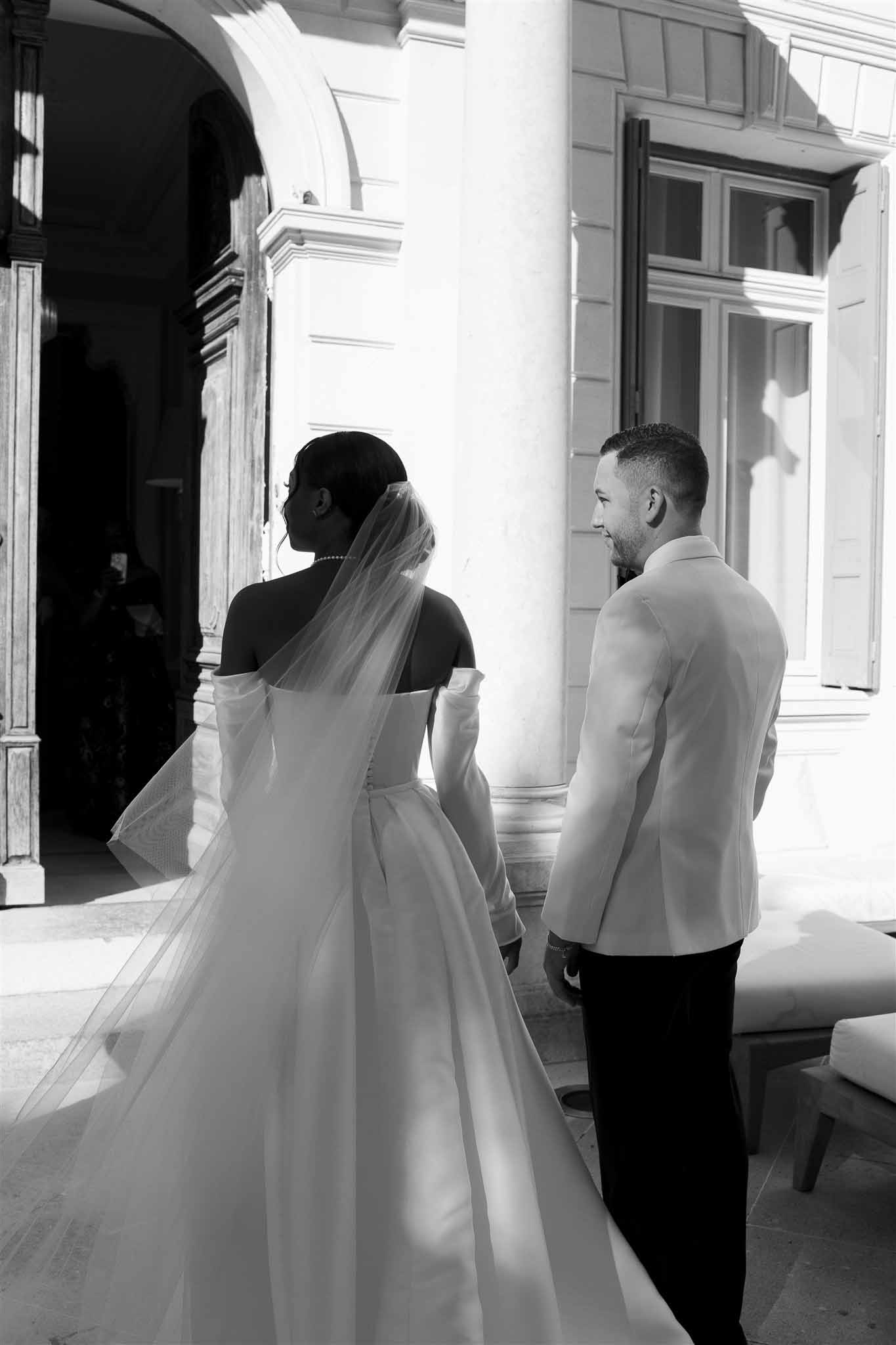 Bride and groom in elegant interior hallway with arched windows and dramatic lighting