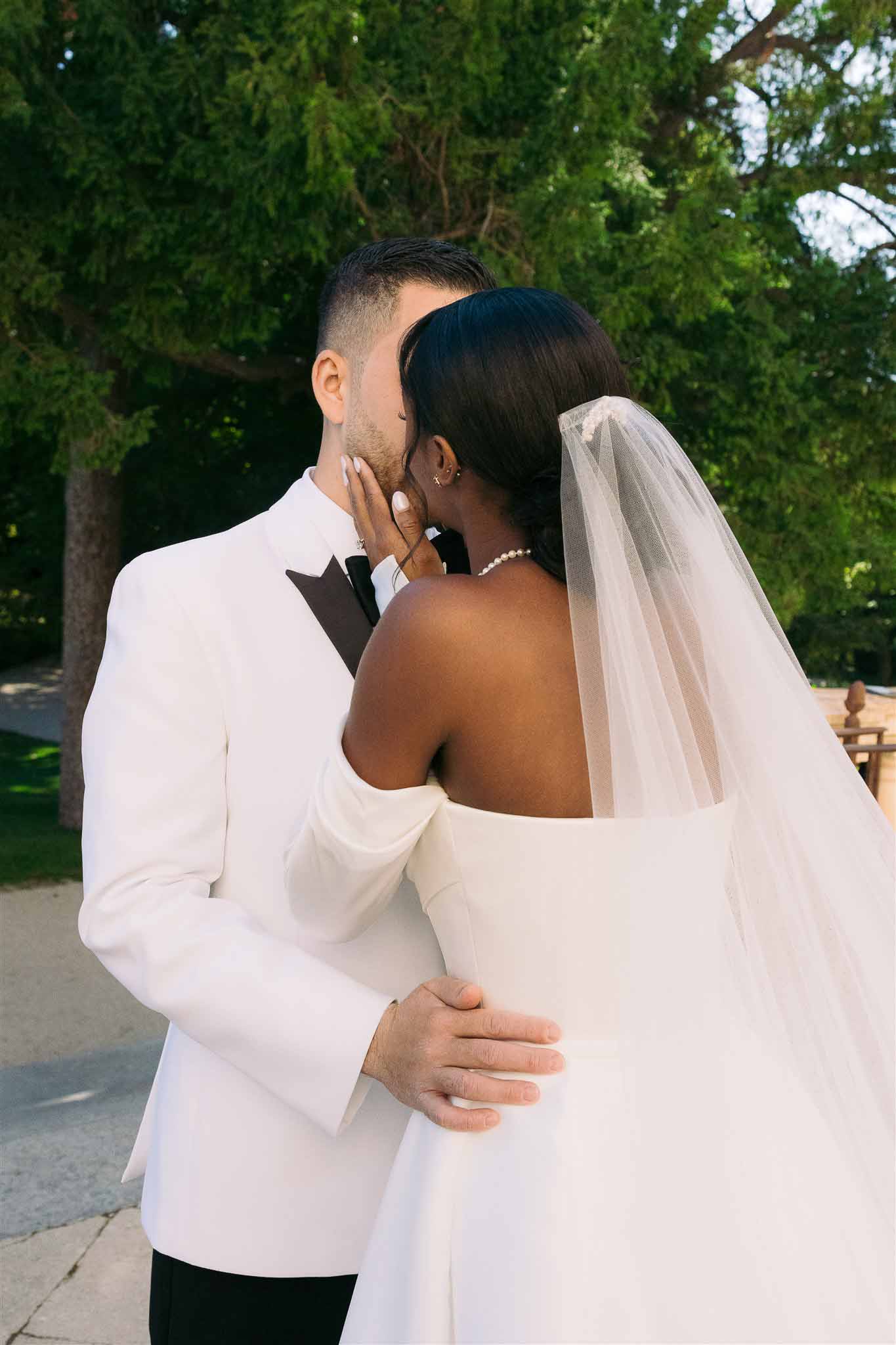 Bride and groom in intimate portrait embracing in garden setting with evergreen trees