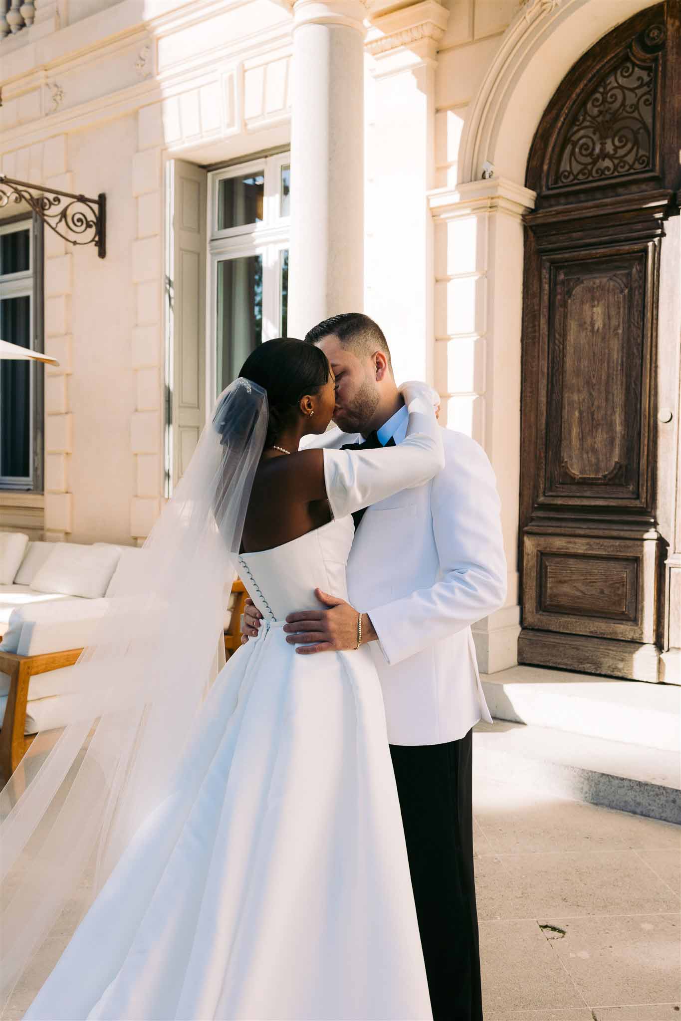 Bride and groom sharing kiss in elegant courtyard with neoclassical architecture and ornate details