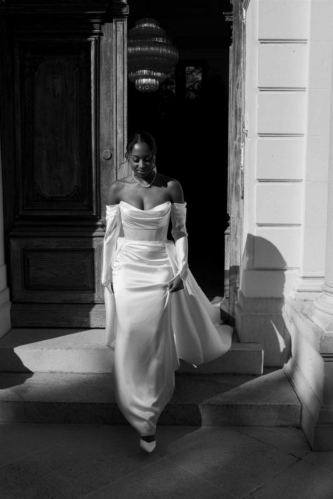Bride in off-shoulder gown walking through architectural passageway with contrasting doors